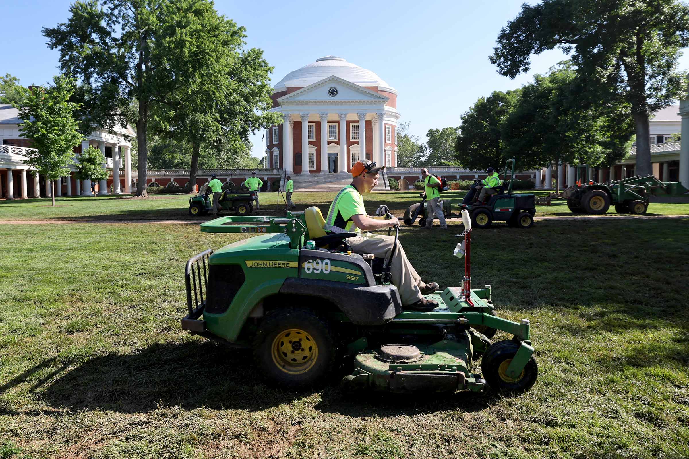 Landscaper Daniel Thacker drives a mower to trim some of the grass and help pull it out of the mud. 
