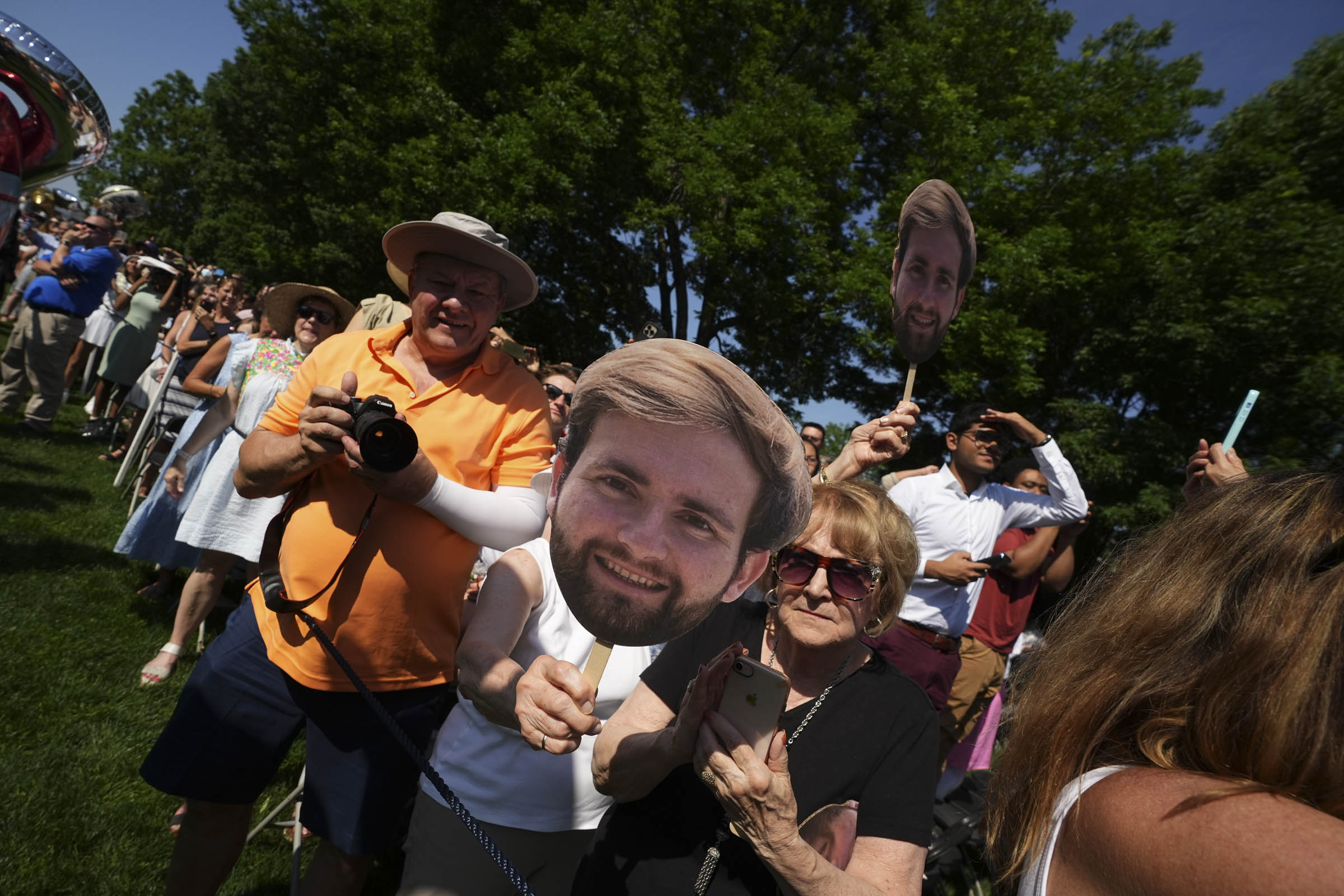 A student’s family members hold large cardboard cutouts of their graduate’s face.