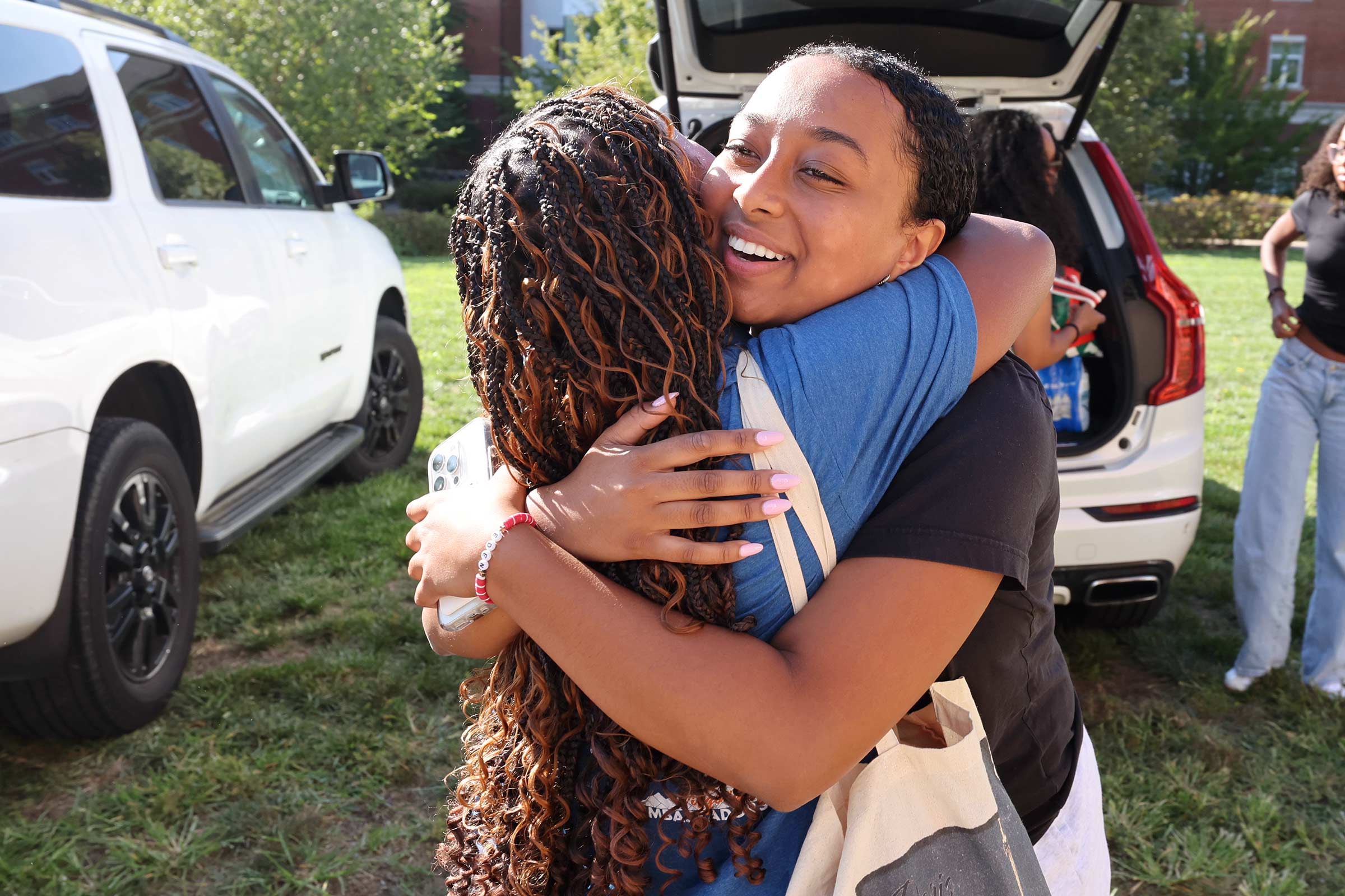 Student and parent embrace in front of their car