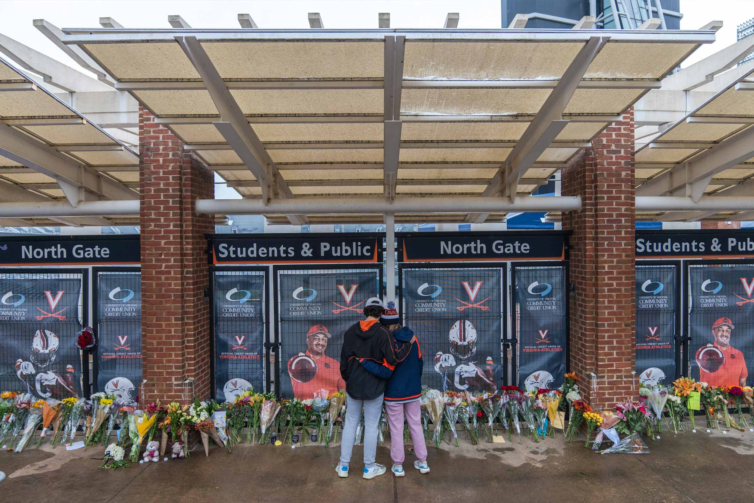 Students embracing each other in front of a memorial for the football players who were lost in November