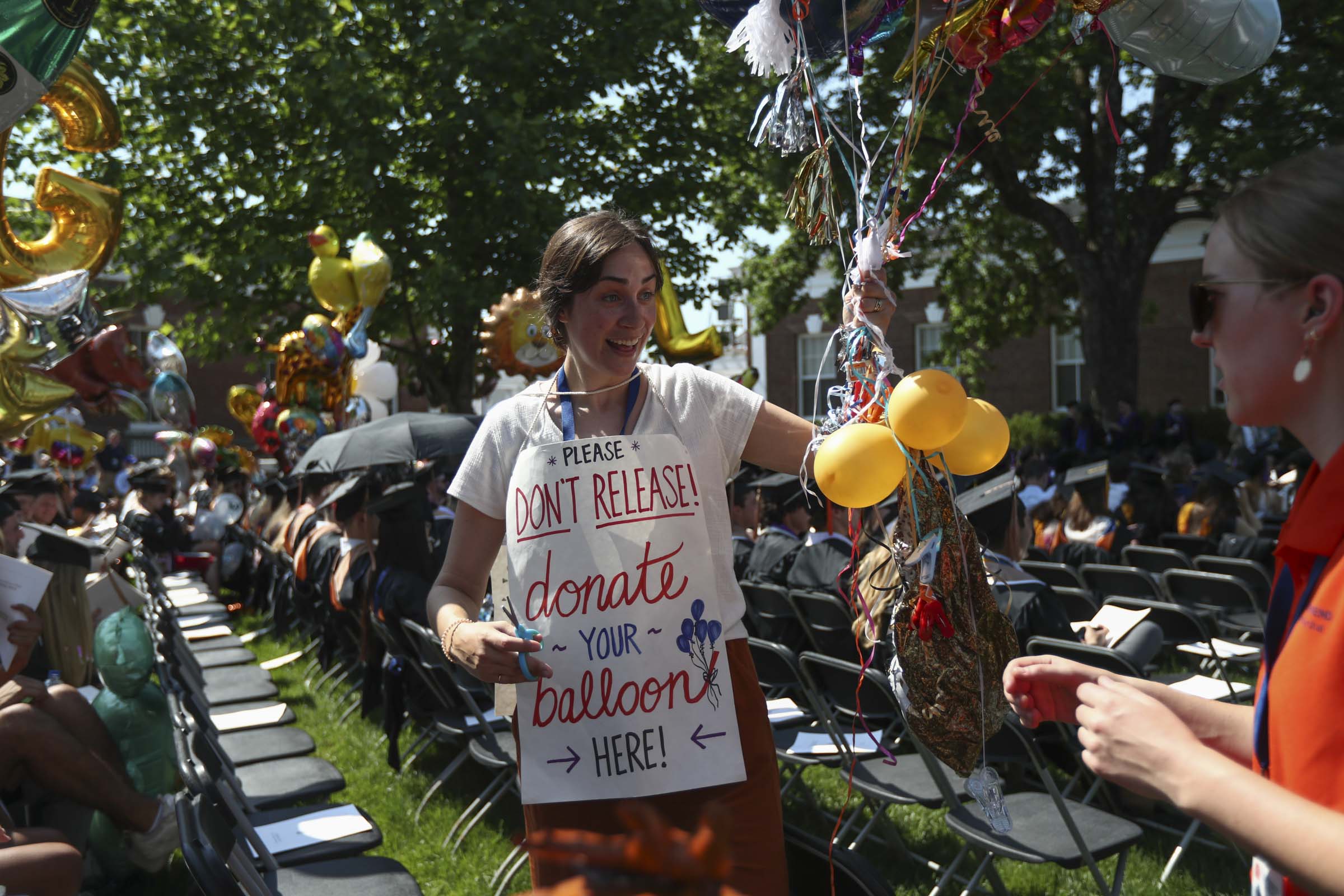 A woman wears a sign asks students not to release their balloons, but to instead let her collect them for the UVA Children's Hospital.
