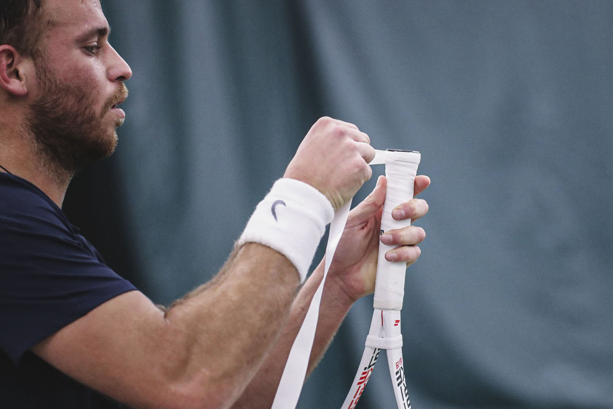 Botzer retapping his tennis racquet 