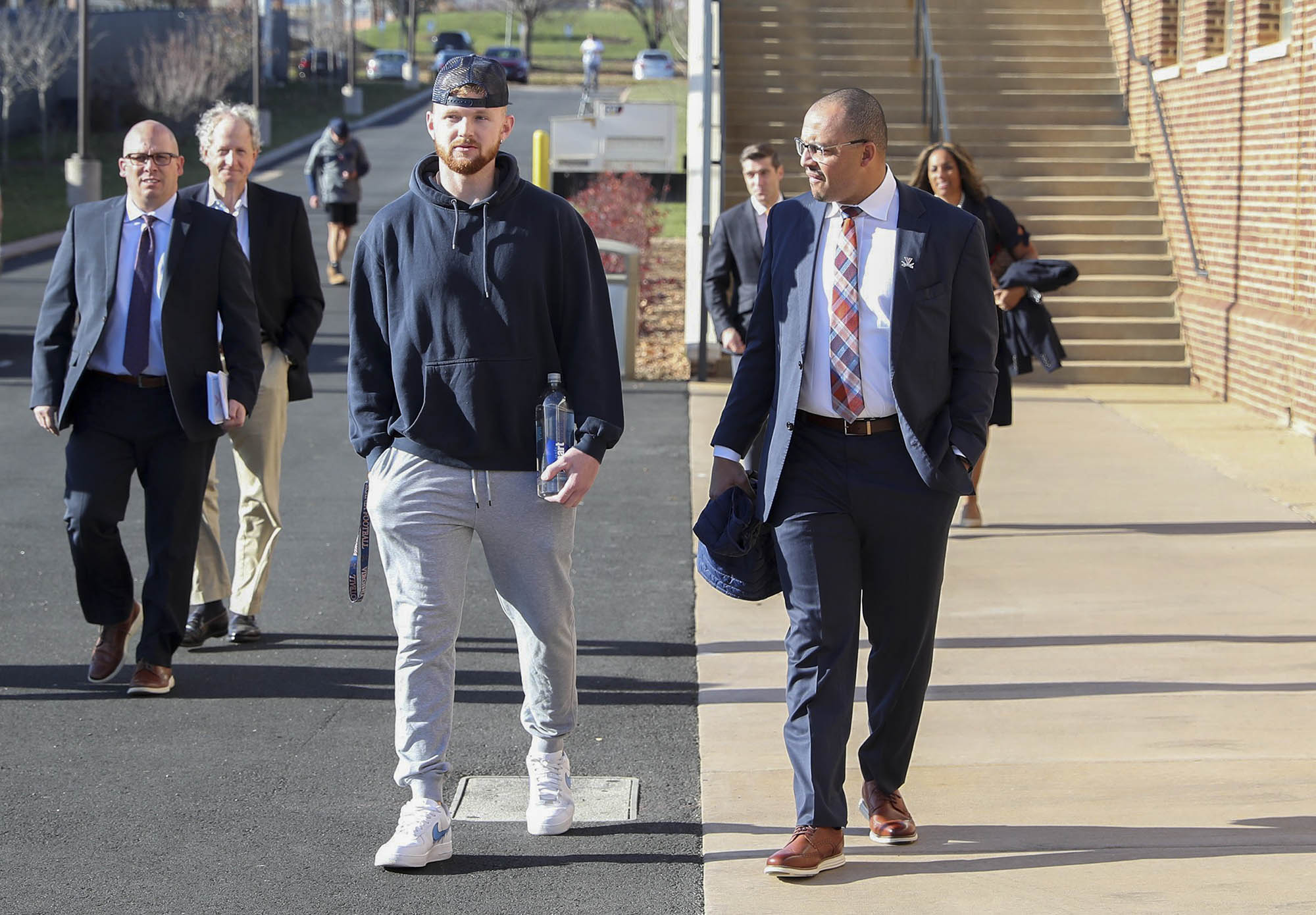 quarterback Brennan Armstrong, left, walks with Elliott, right a road