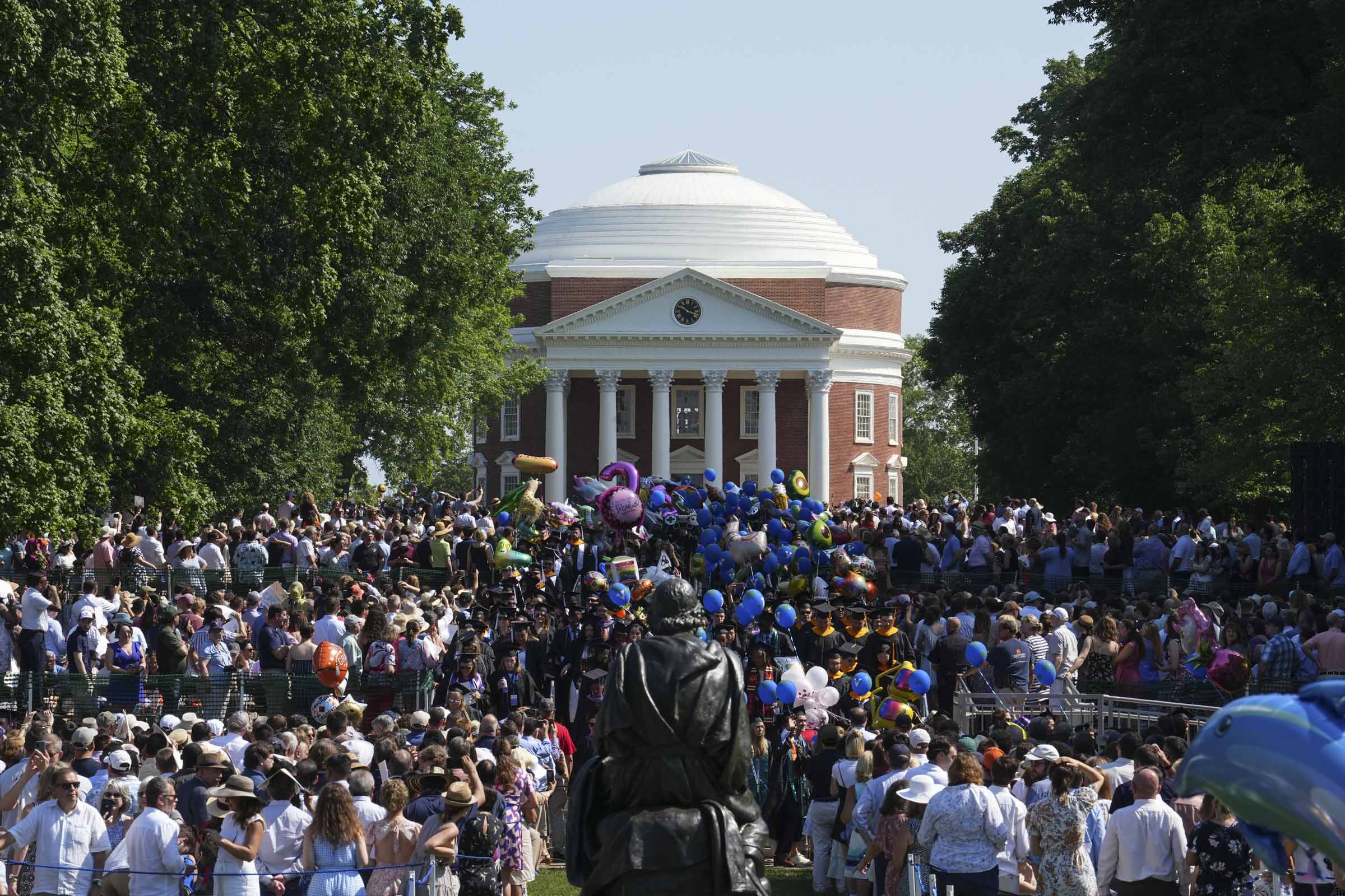 Hundreds of spectators turn to view the Rotunda as a wave of students toting blue balloons saunters down the Lawn.