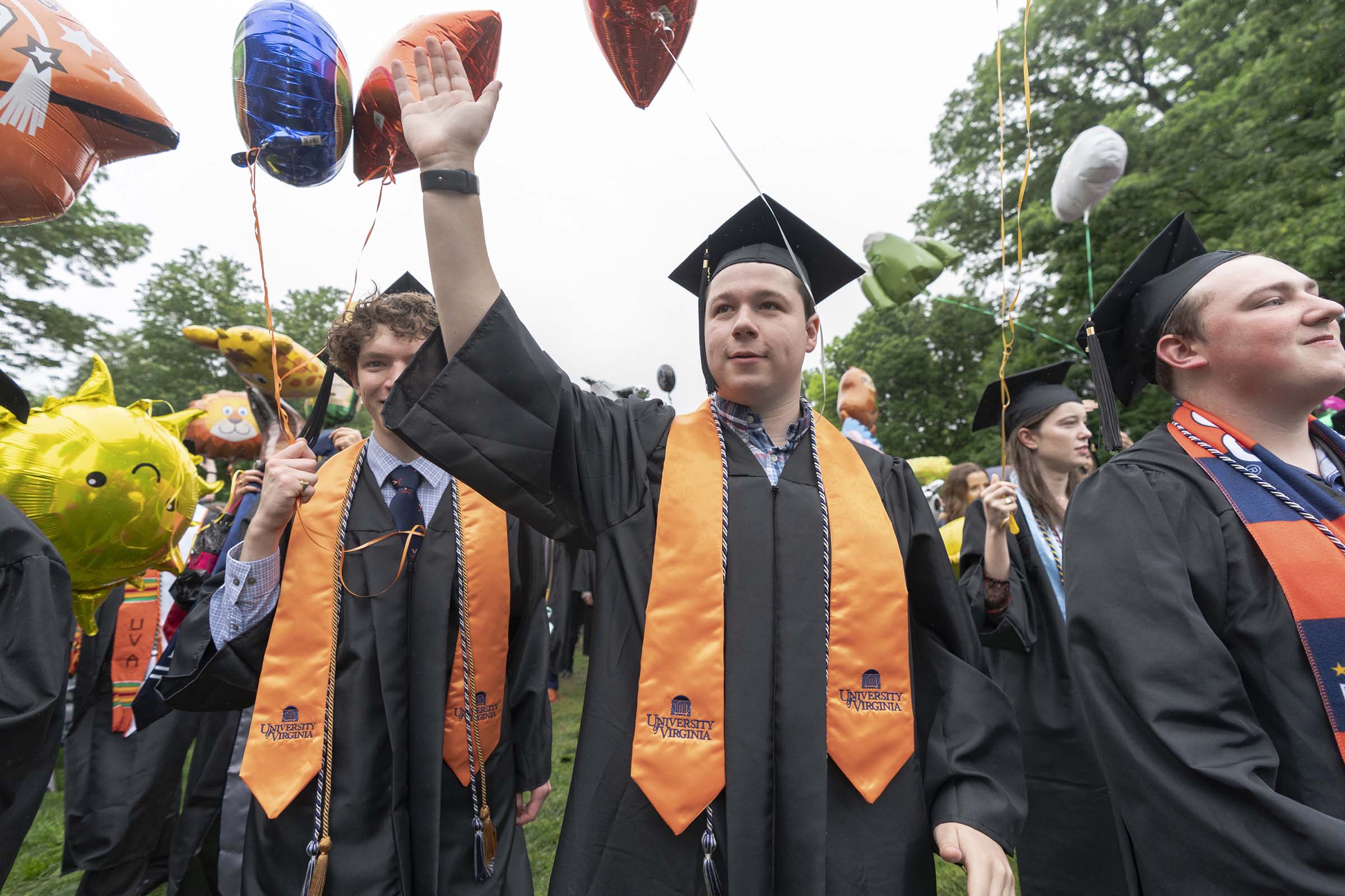 Graduating students wearing orange stoles processing down the Lawn