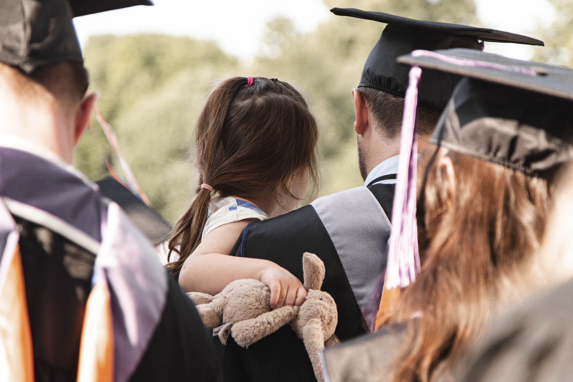 From behind a graduate holding his daughter