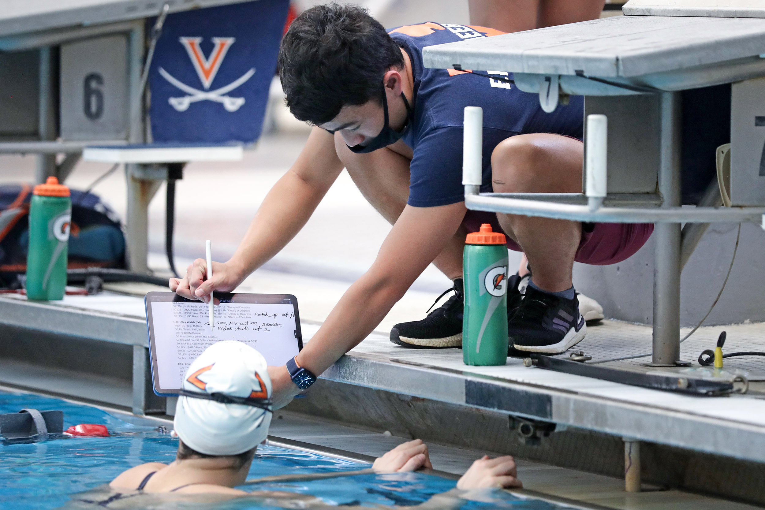Swimming coach showing UVA swimming information on a clipboard while in the pool
