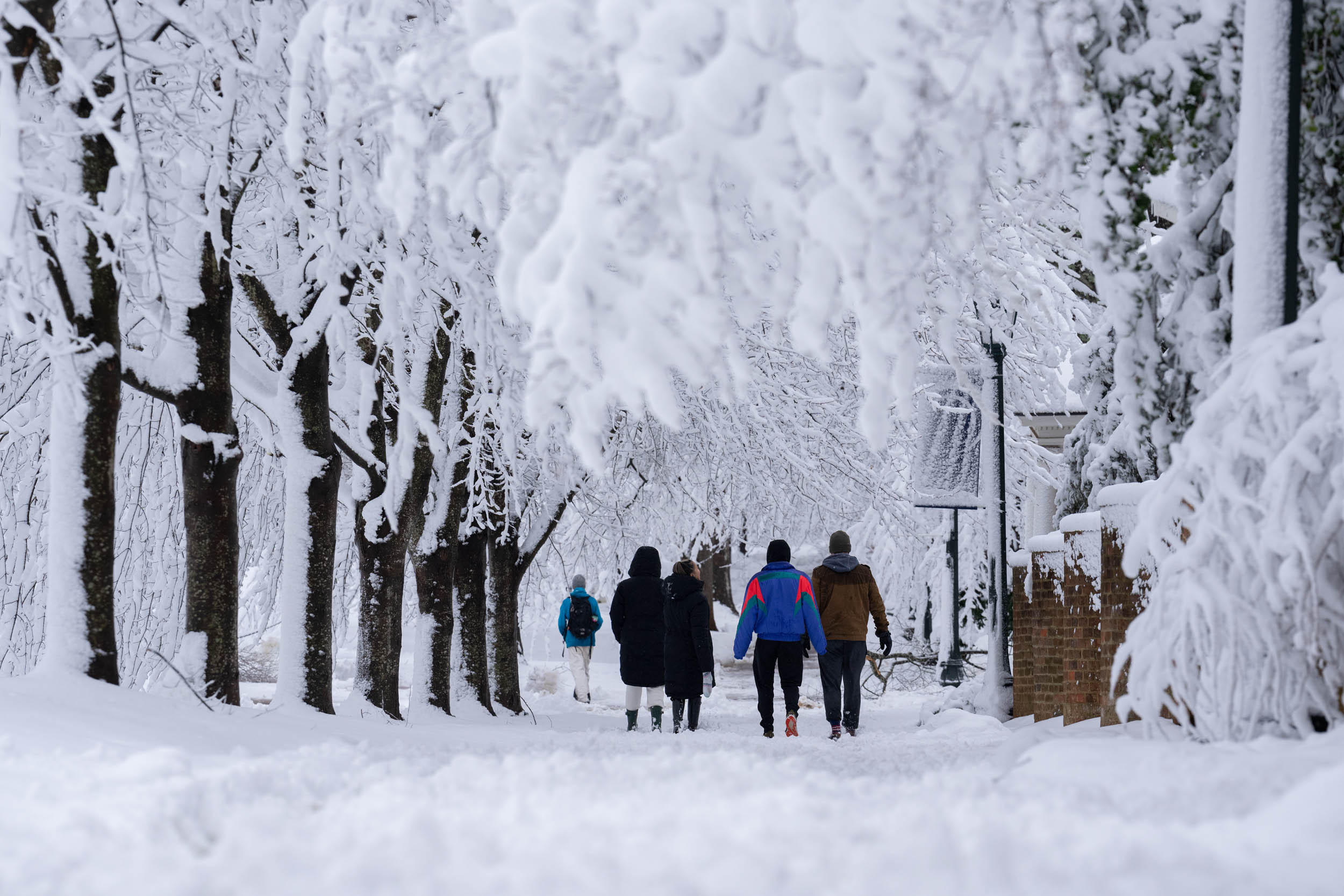 Students walking on a snow covered sidewalk on grounds