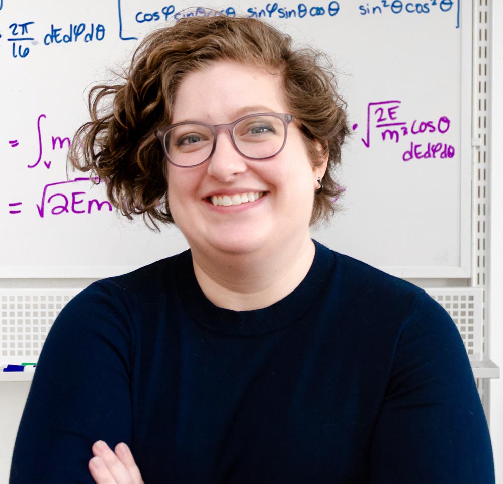 Hayley Williamson standing in front of a whiteboard with equations written on it