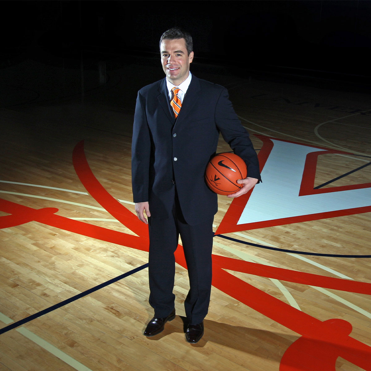 Tony Bennett standing center court at University Hall holding a basketball.