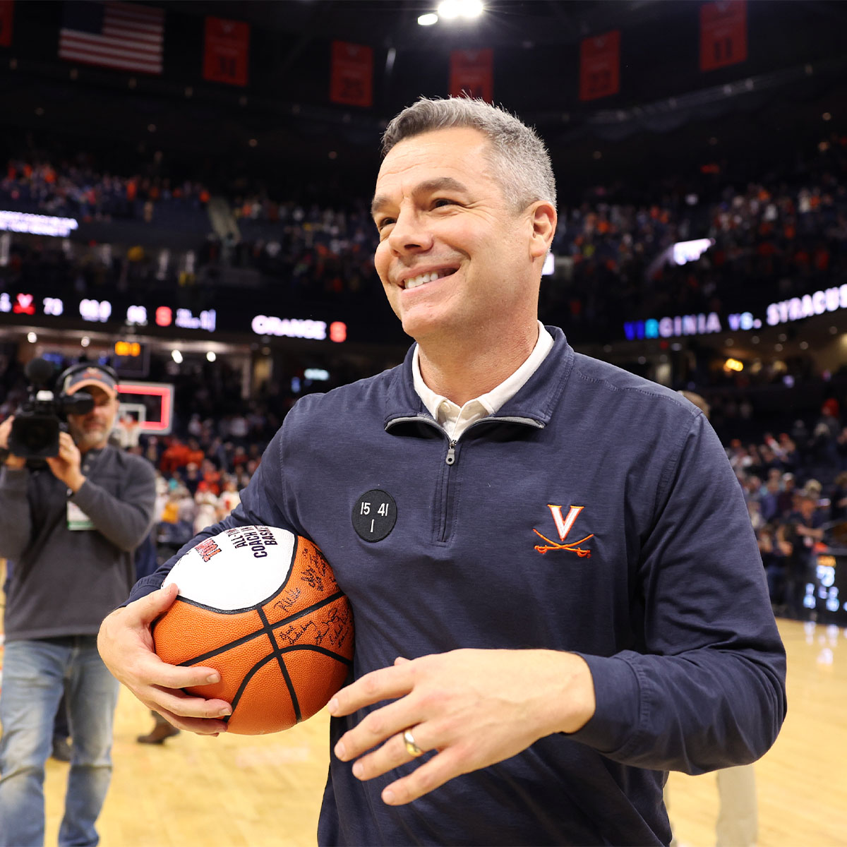 Tony Bennett holding an autographed ball at a celebration in John Paul Jones Arena.