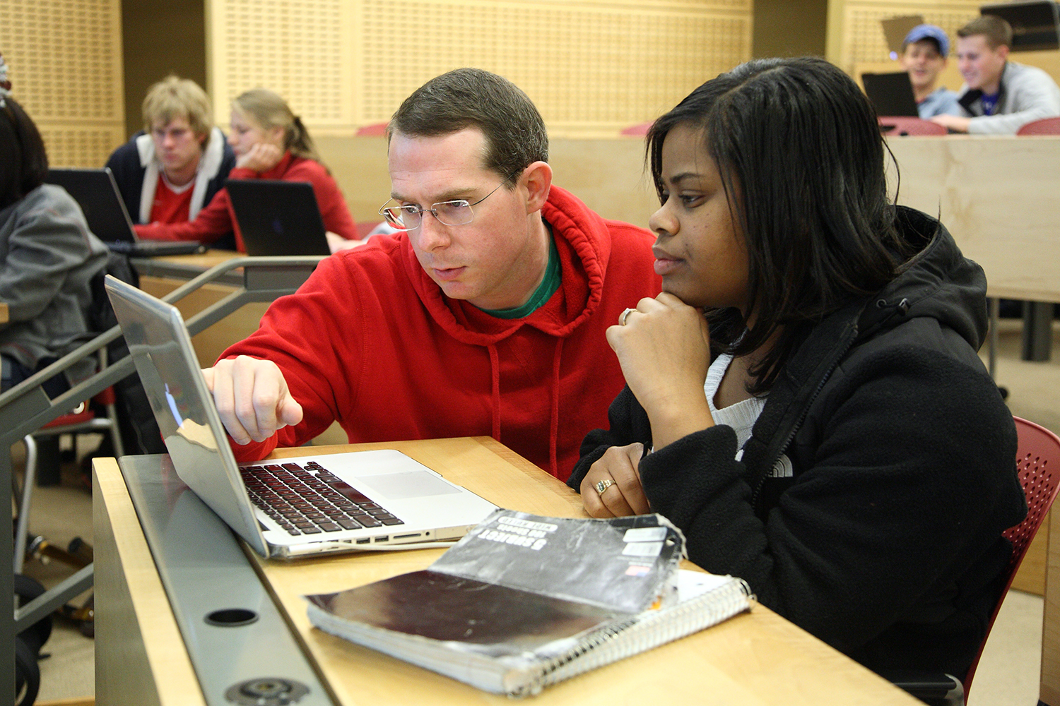 Two people looking at a laptop together in a classroom