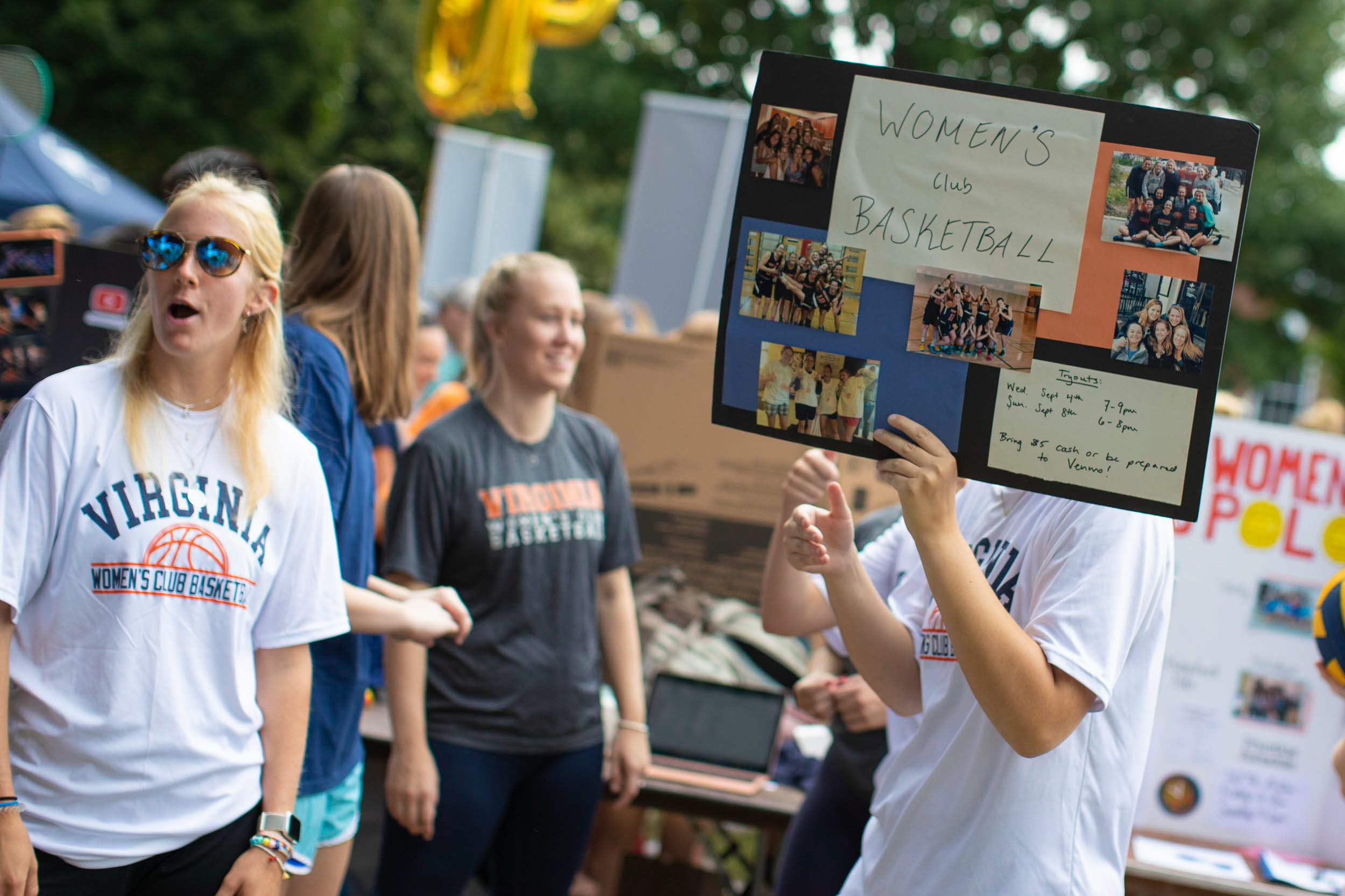 Activity fair with a student holding a sign that says Women's Club Basketball
