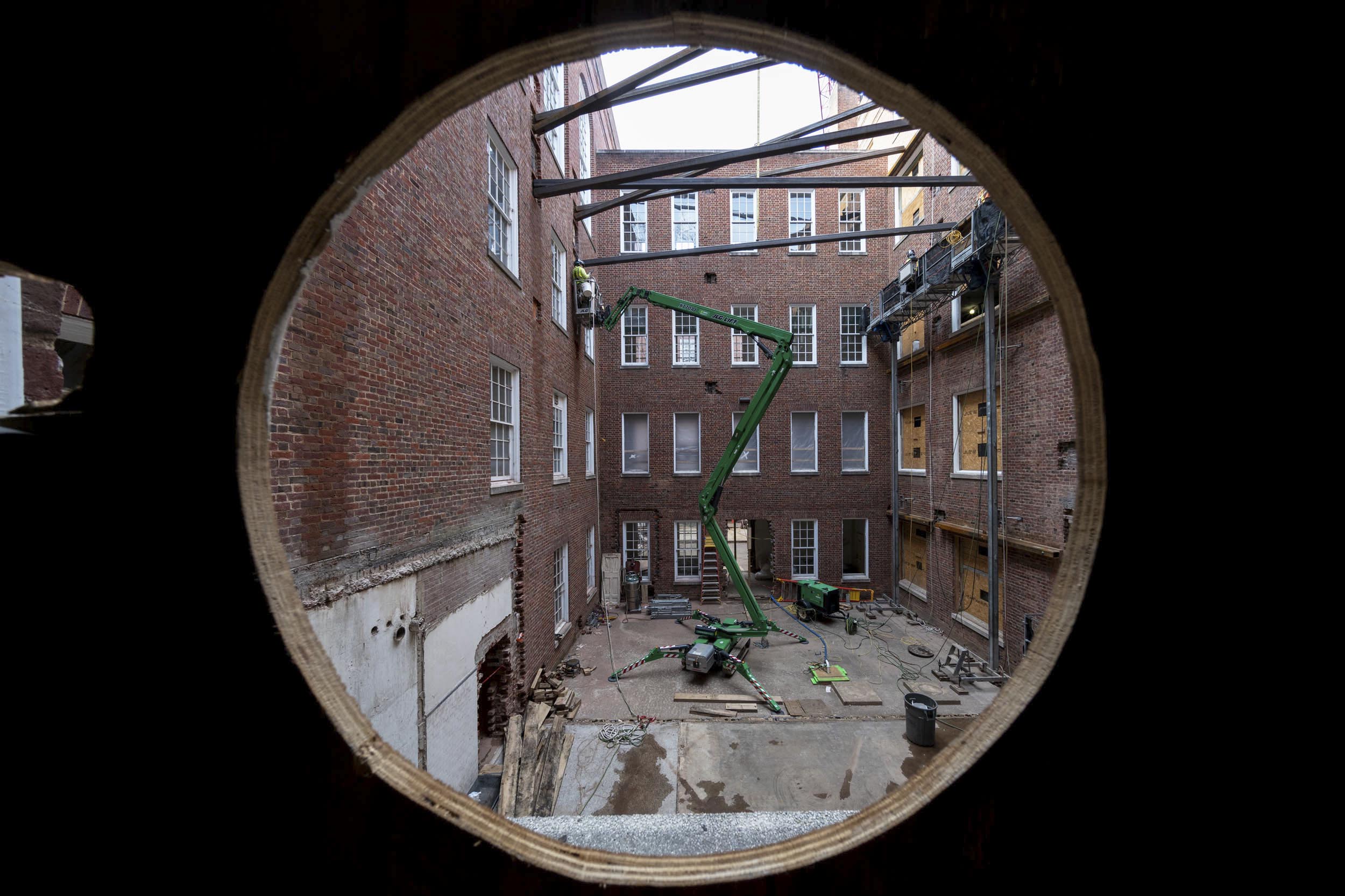 Looking out from where a circle window is observing construction of the Alderman Library