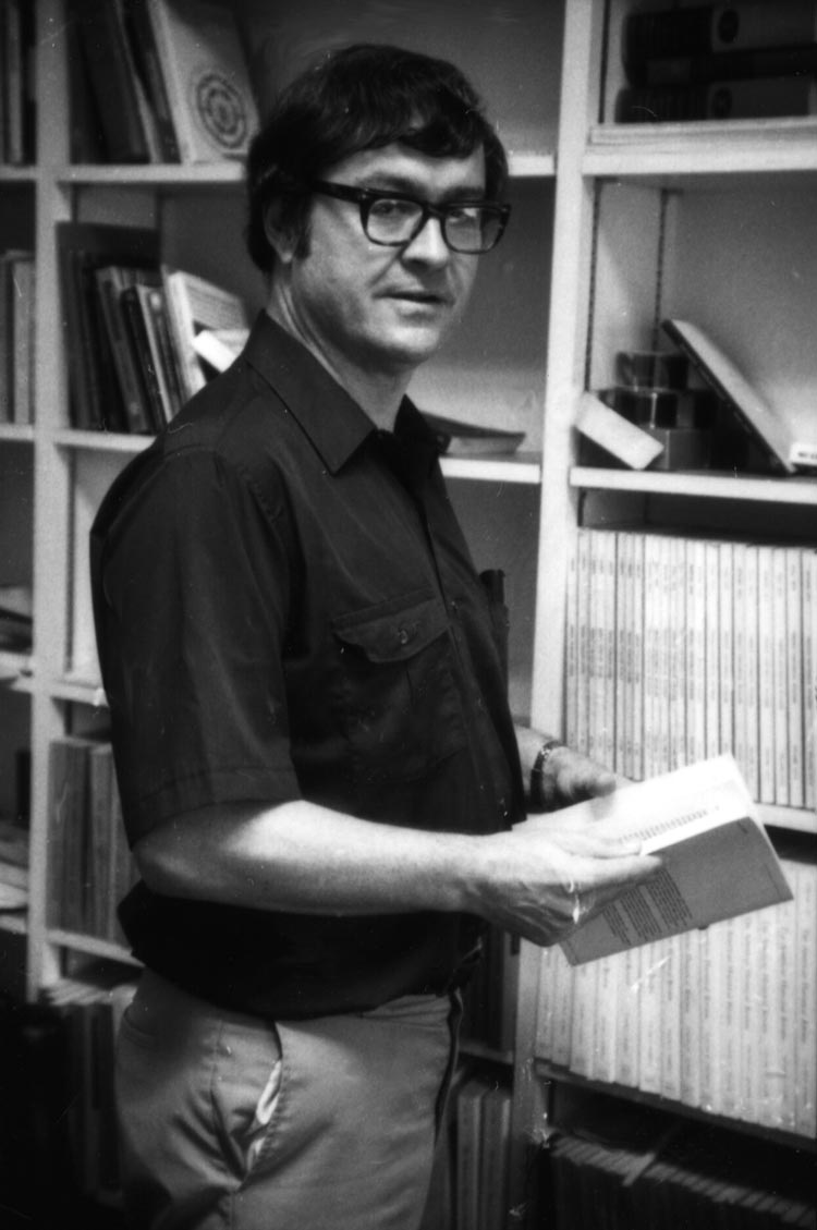 Sedgwick holding a book looking at the camera in a black and white image