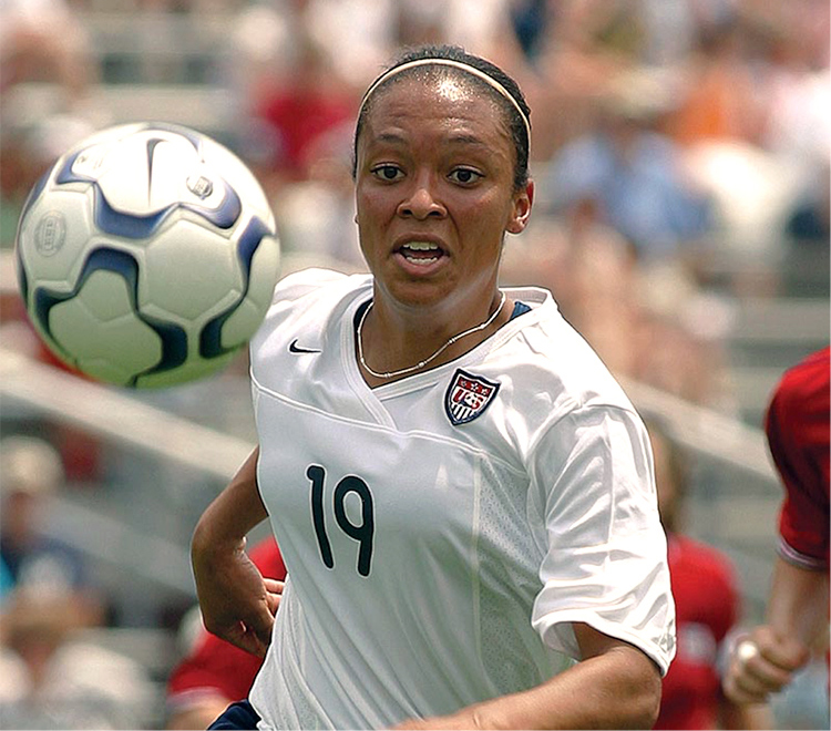 Angela Hucles preparing to kick a soccer ball on the field during a match