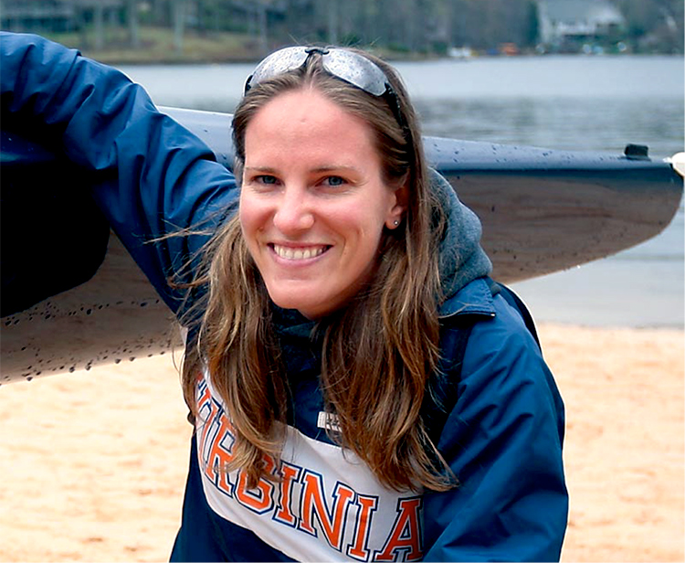 Angela Kok kneels next to her canoe smiling at the camera