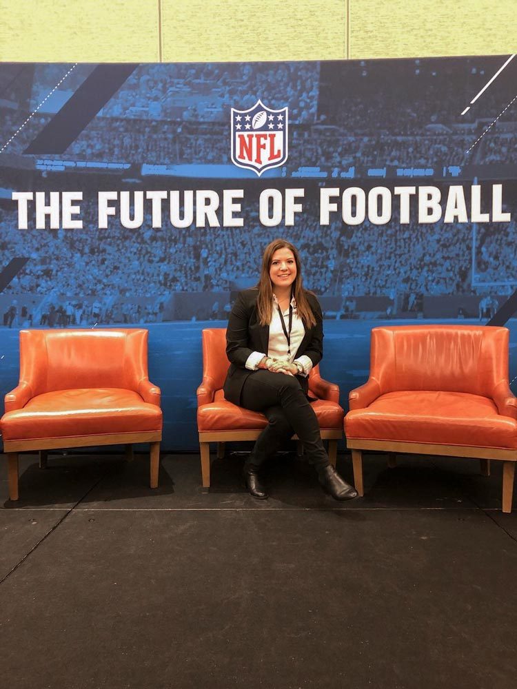 Meurer sits in orange chairs in front of a picture that says The Future of Football