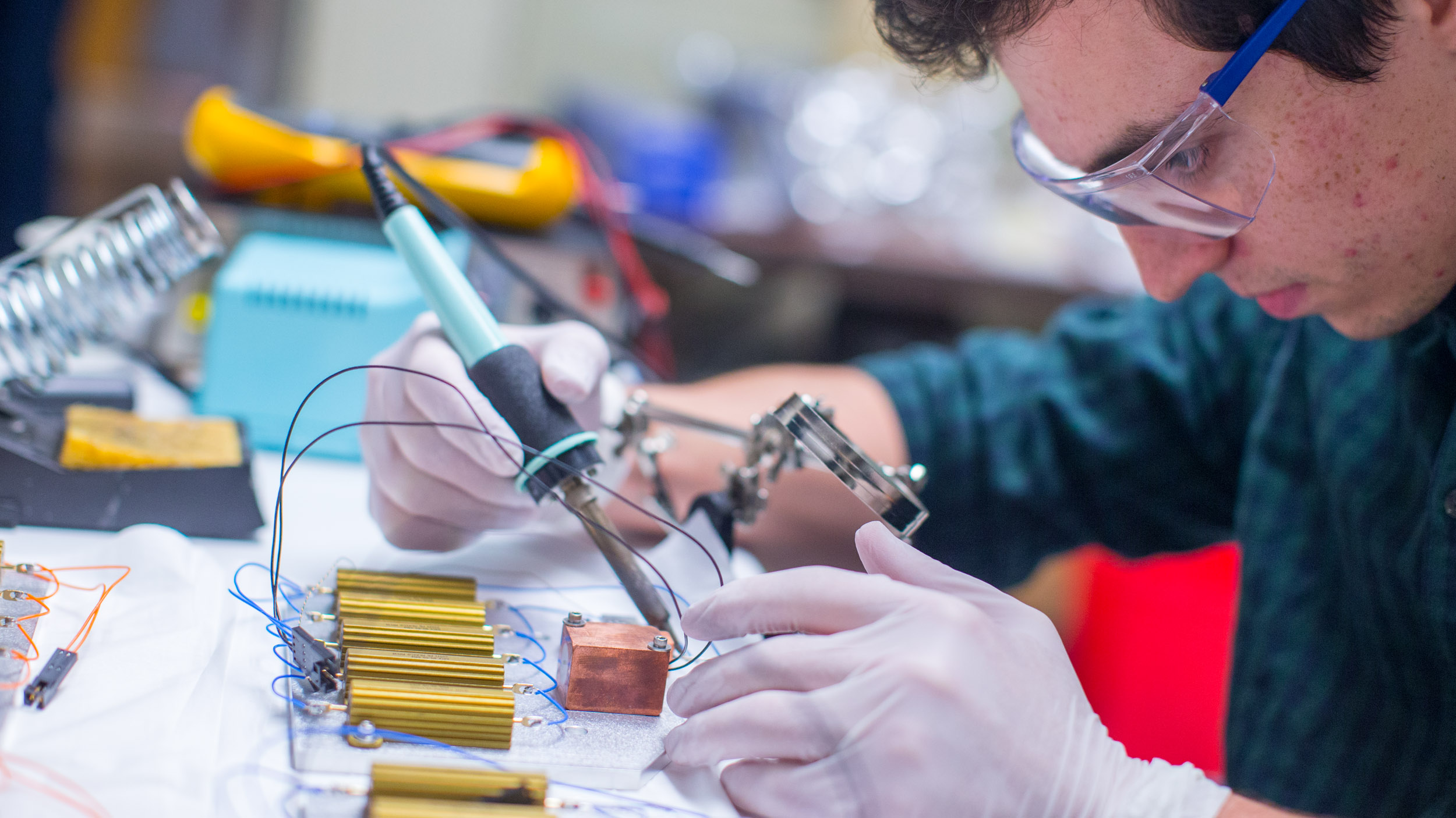 Recent UVA graduate and now lab technician Matthew Hall assembles electronic circuitry for APOGEE’s thermal warm-up system.