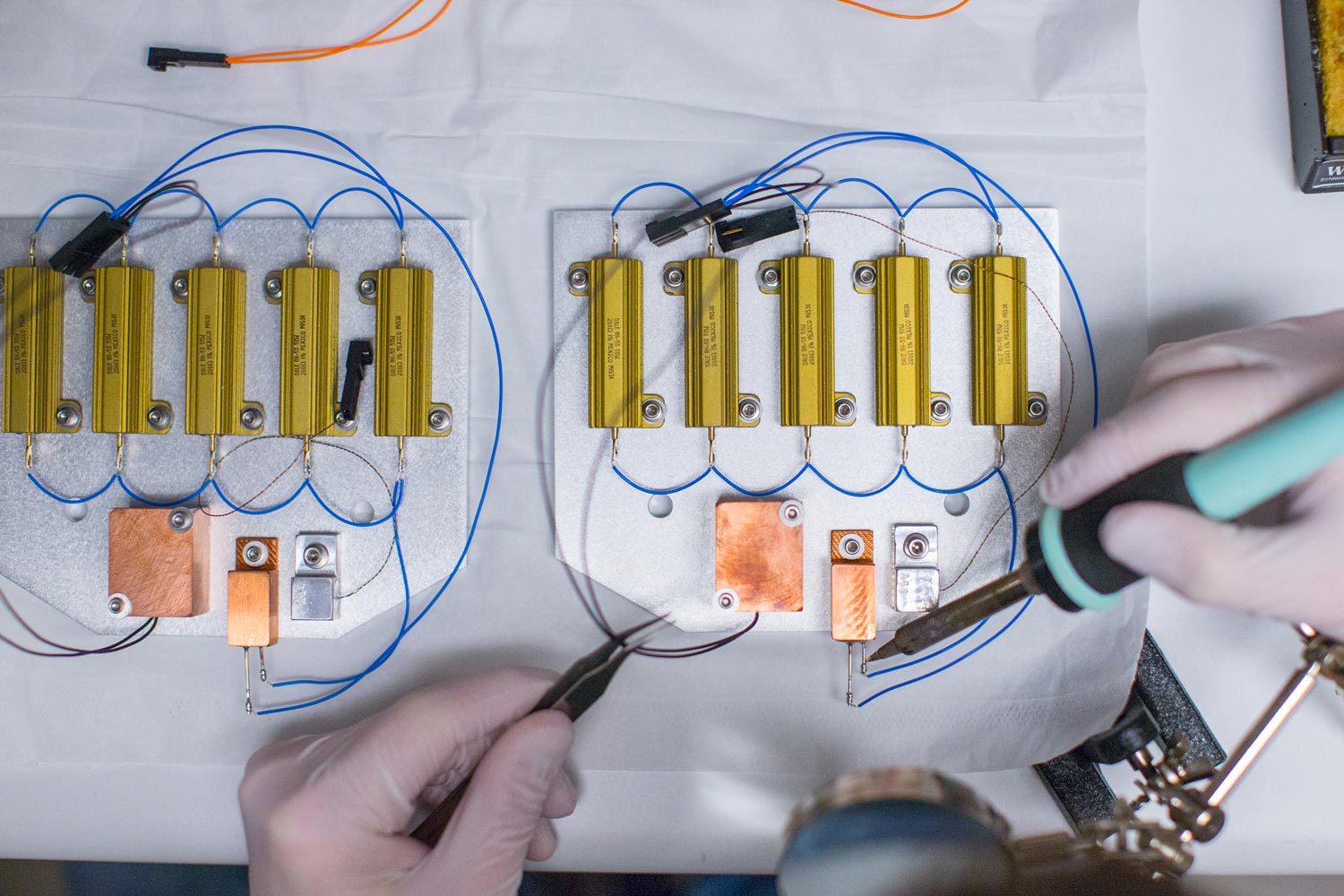 Person moving wires and soldering them to a medal