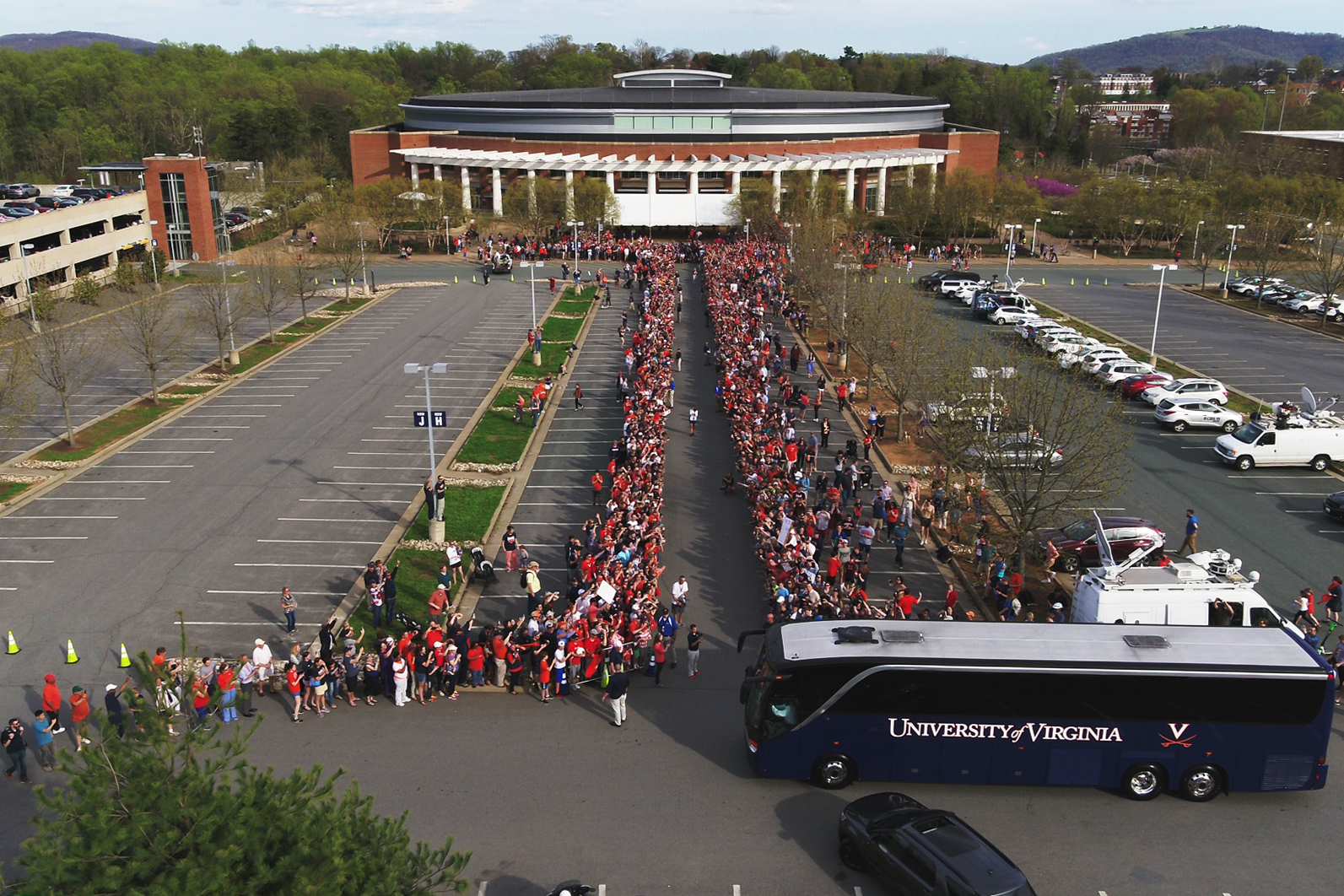 UVA bus carrying the basketball team pulls up to a parking lot lined with cheering fans