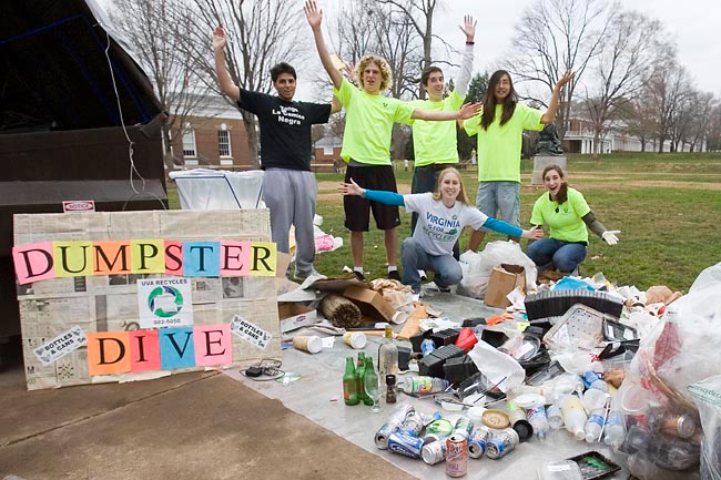 Group of students stand behind a tarp full of recyclable materials 