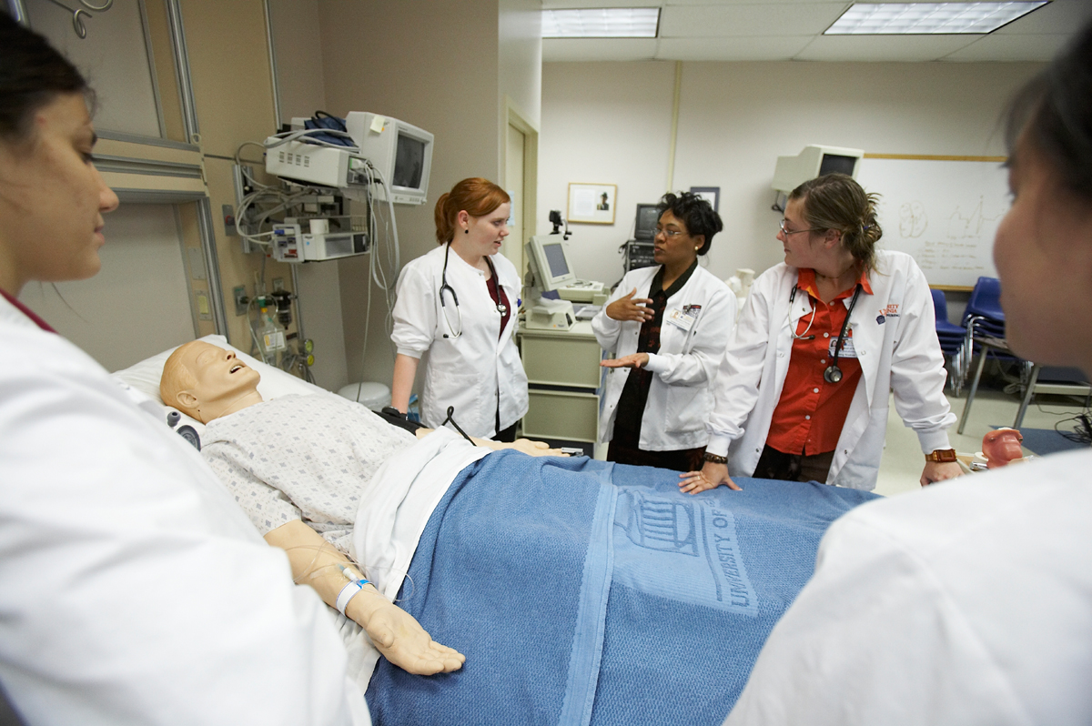 Nursing students in a simulator lab listening to an instructor
