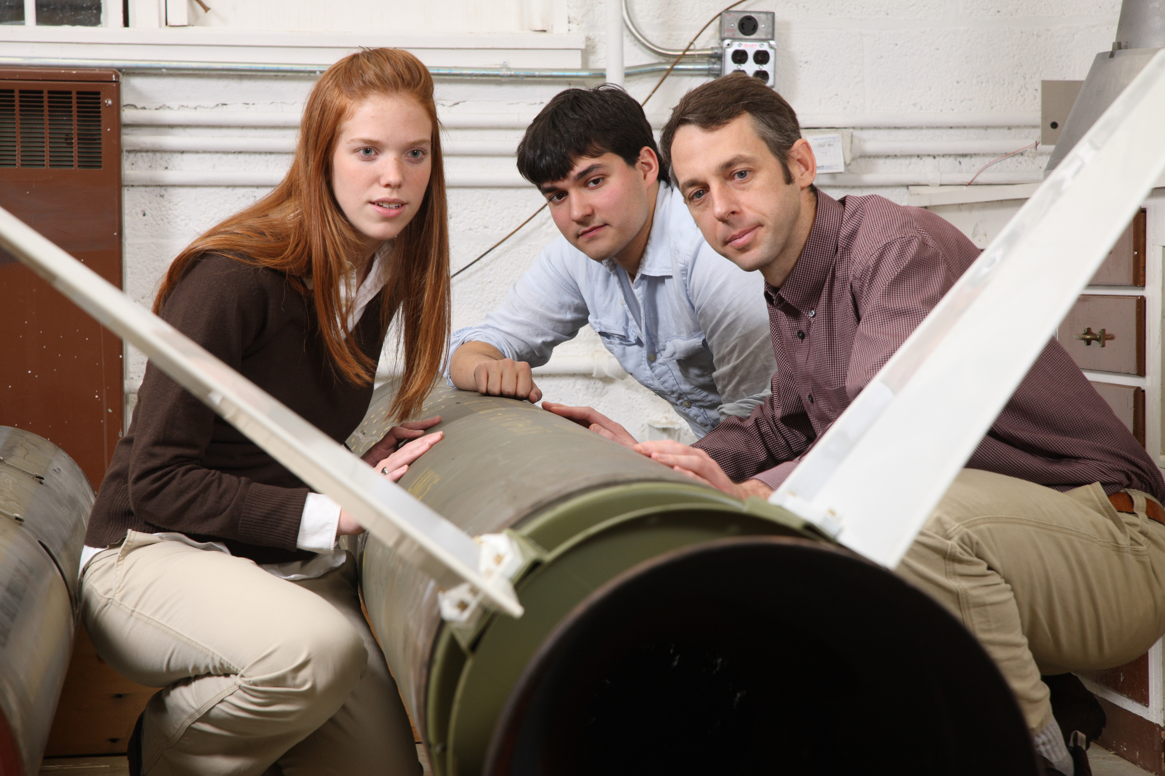 Elizabeth Martin Ryan Johnson, and Assistant Professor Christopher Goyne inspect a rocket