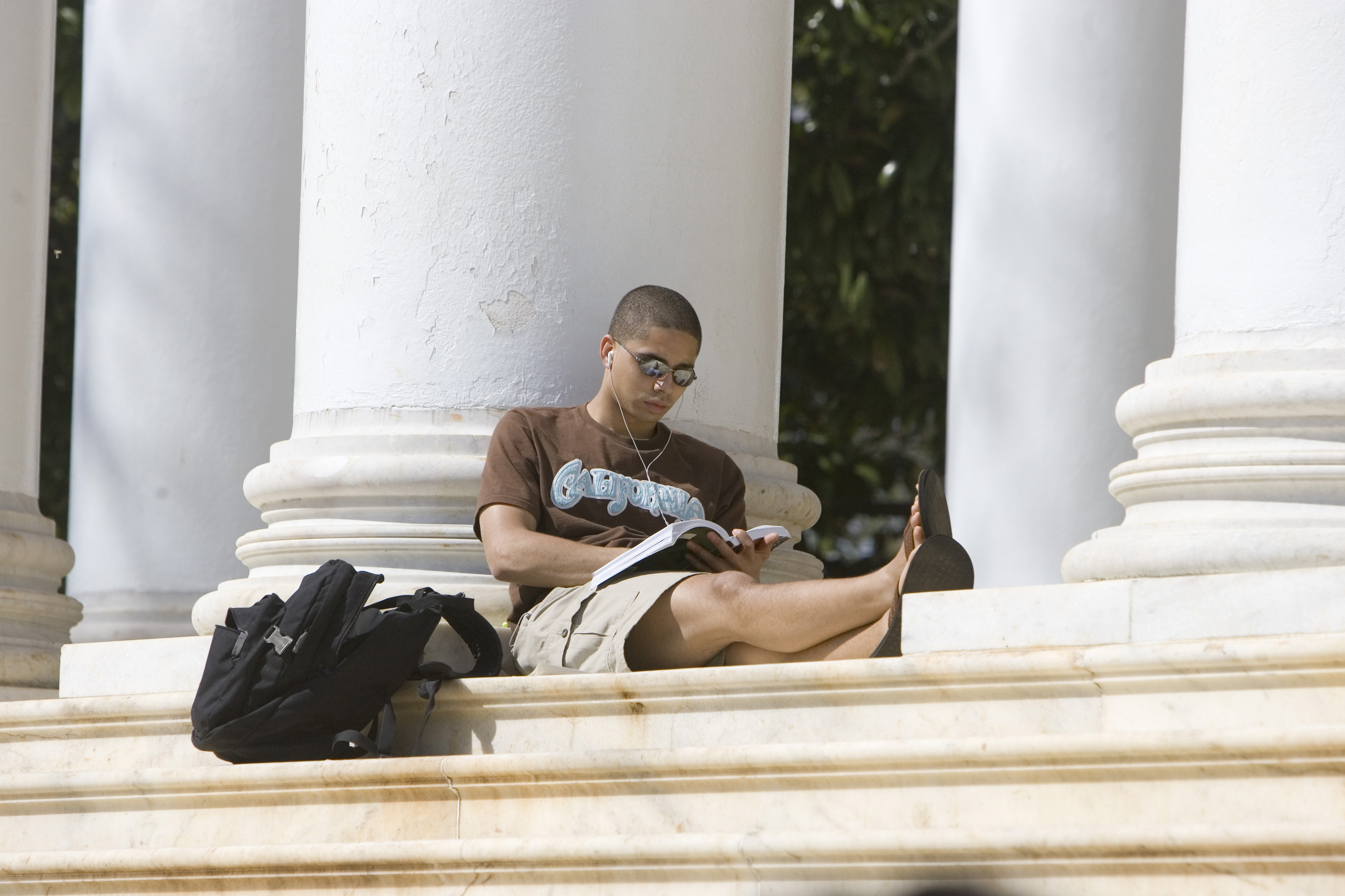 Students sitting between the columns of the Rotunda reading a book