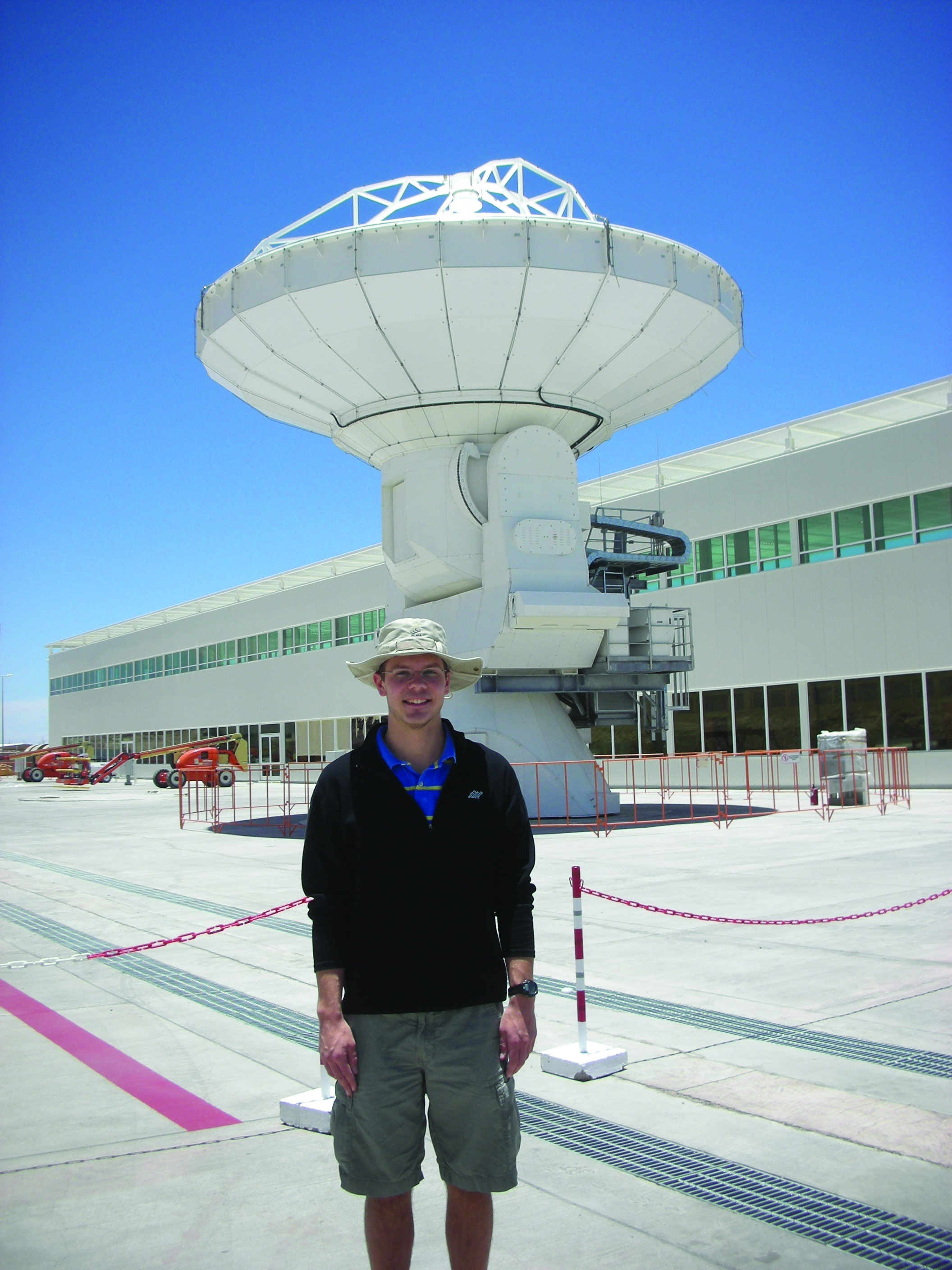 Ian Czekala stands in front of a massive telescop