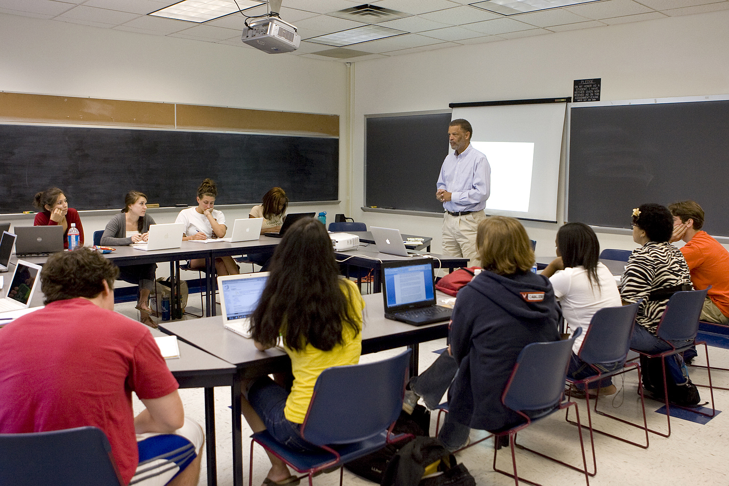 Professor stands in front of  class teaching a group of students