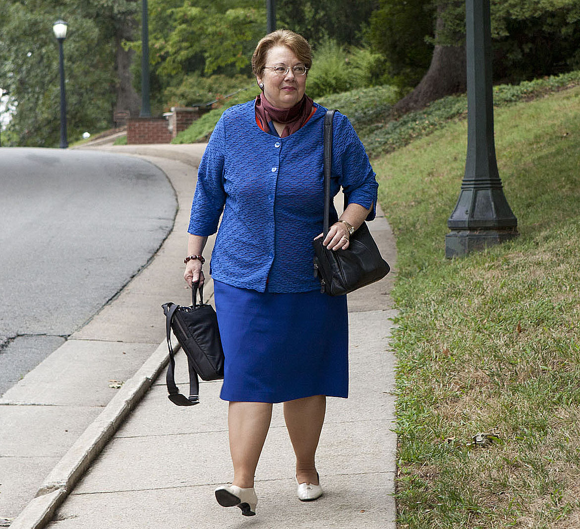 Teresa A. Sullivan walking on a sidewalk carrying her bags