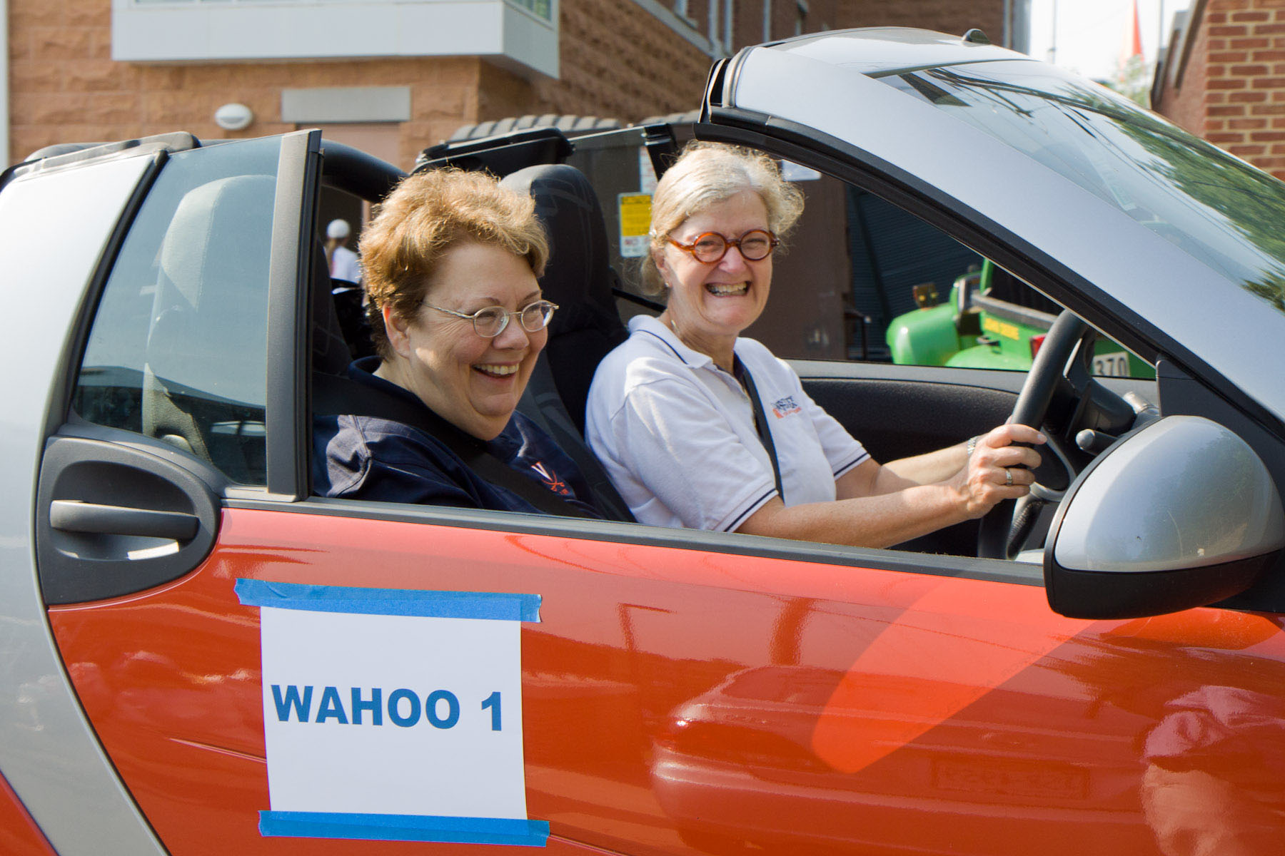 President Sullivan, left, and Pat Lampkin, right, drive in a convertible car