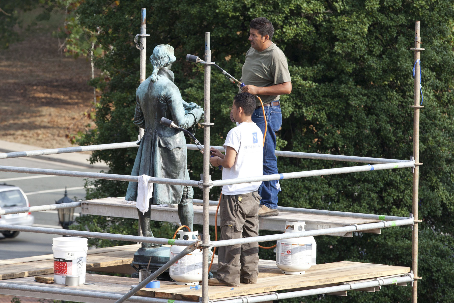 Craftsmen Rene Terrazas and Jacob Cruz, apply a layer of hot wax to a statue of Thomas Jefferso