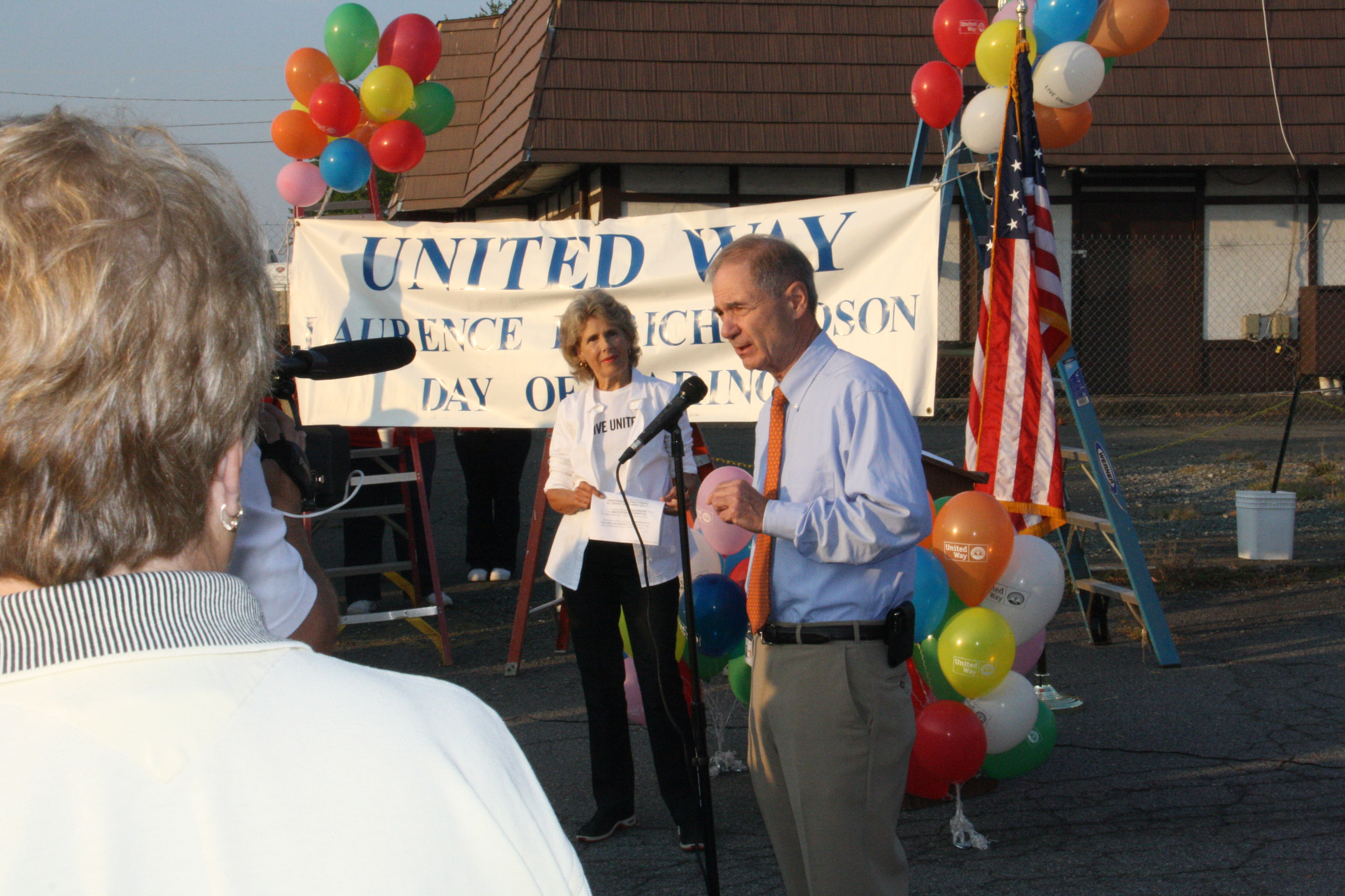 Leonard Sandridge speaking at a microphone to a crowd who gathered at a day of caring event