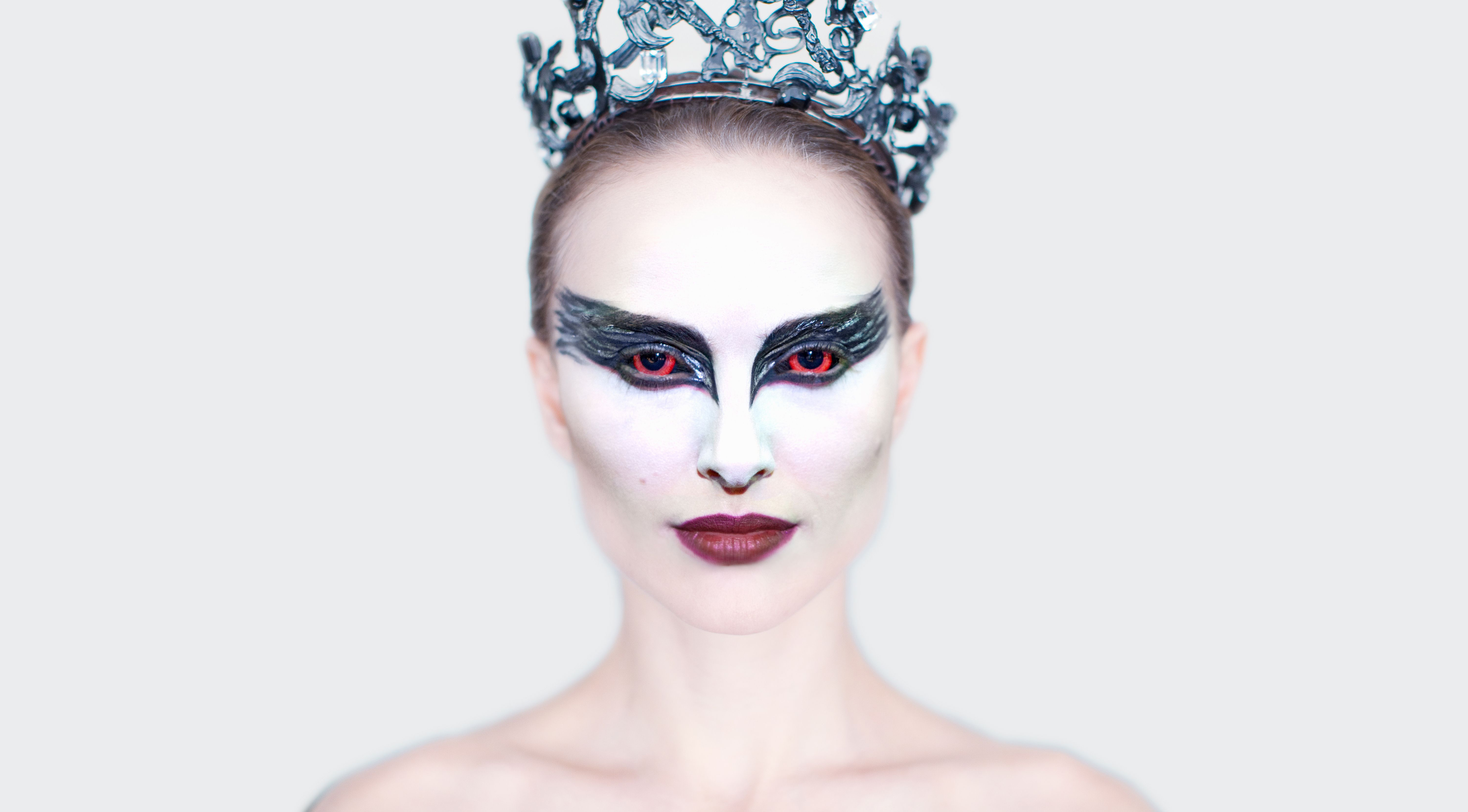 Balerina with a crown, red contact lenses, and thick black makeup around her eyes