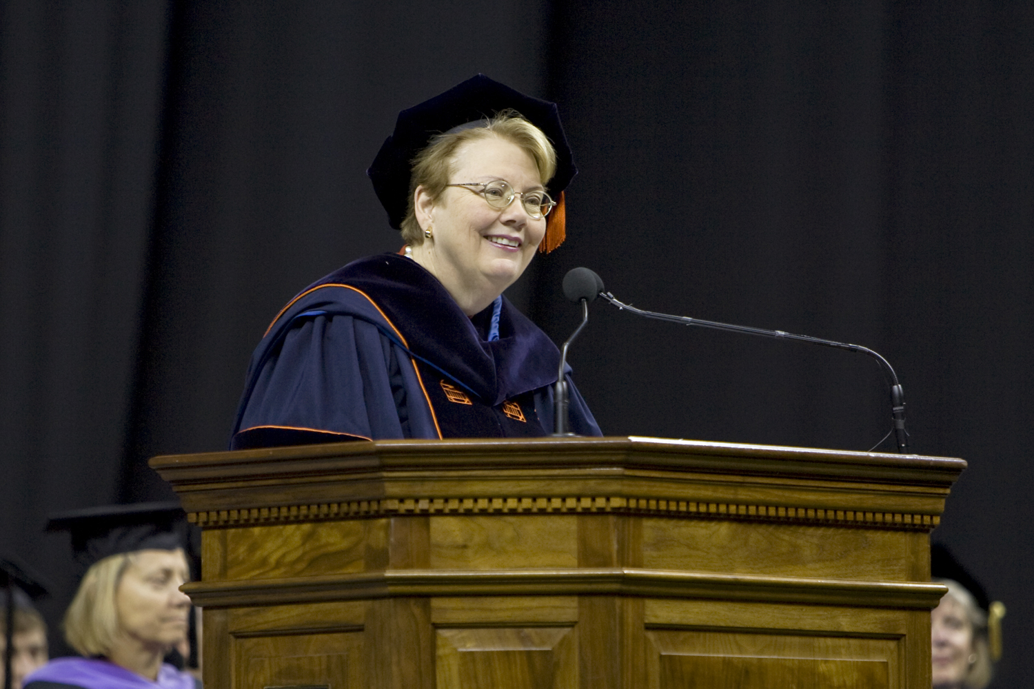 Teresa A. Sullivan speaking at a podium in Graduation attire