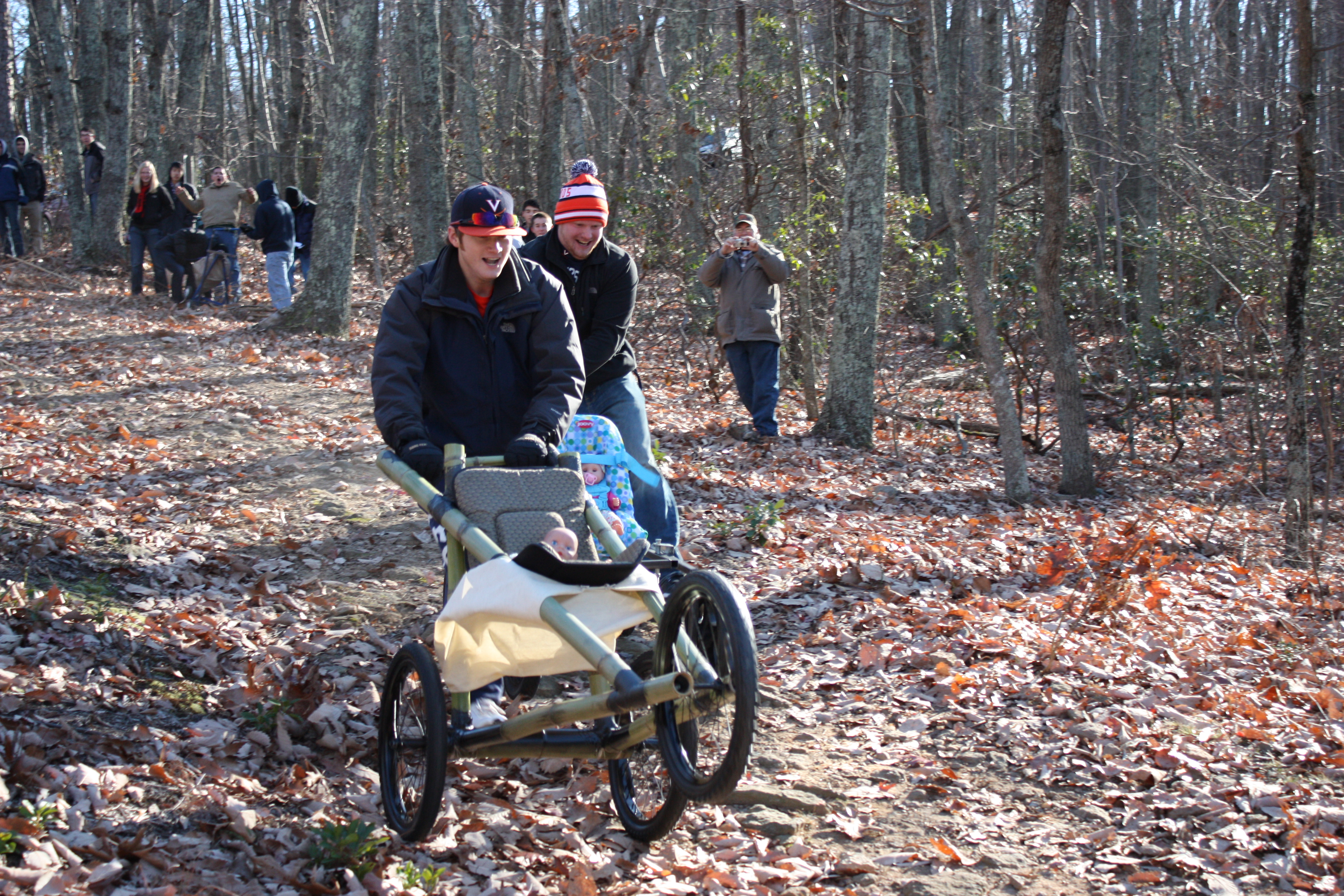 Ryan Slater (front) with his team's  homemade stroller pushing the stroller down a muddy rocky hill