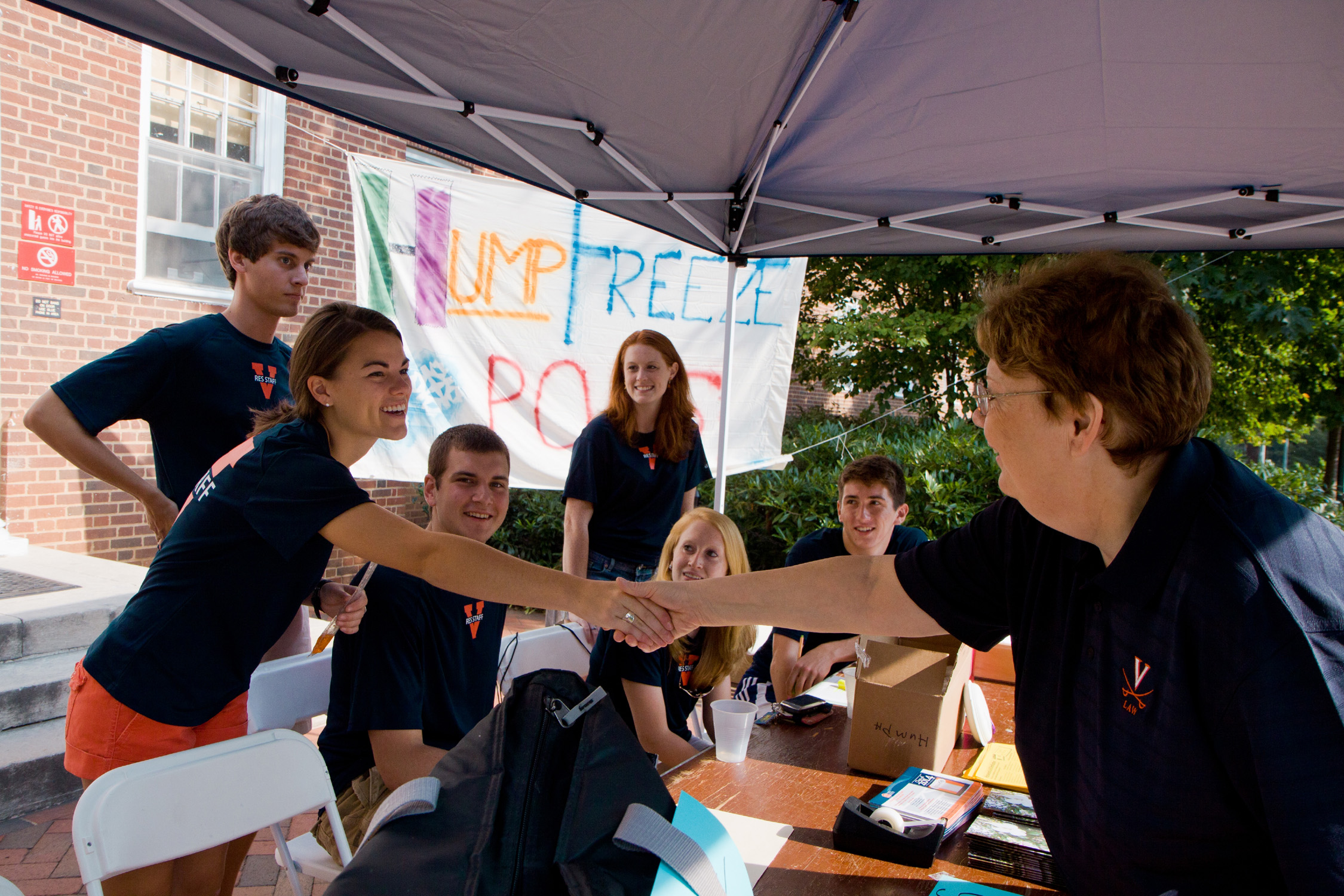 President Sullivan greets students at the greeter table in front of a dorm