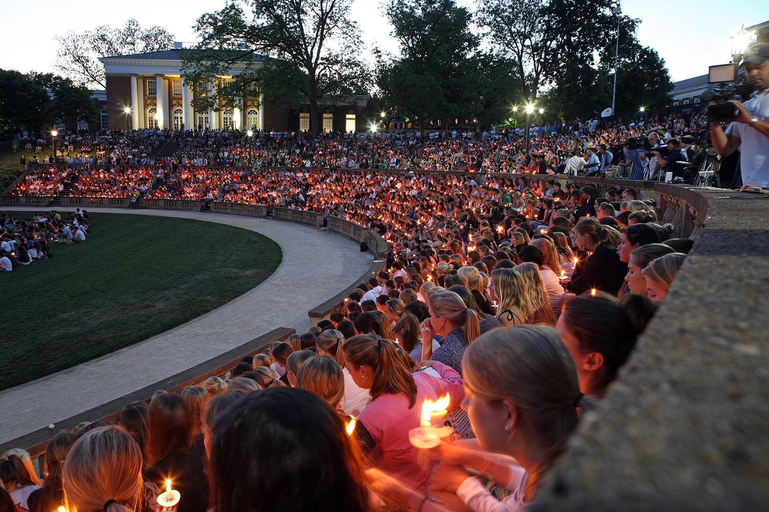 Students holding candles sit in the amphitheater during a vigil for Yeardley Love 