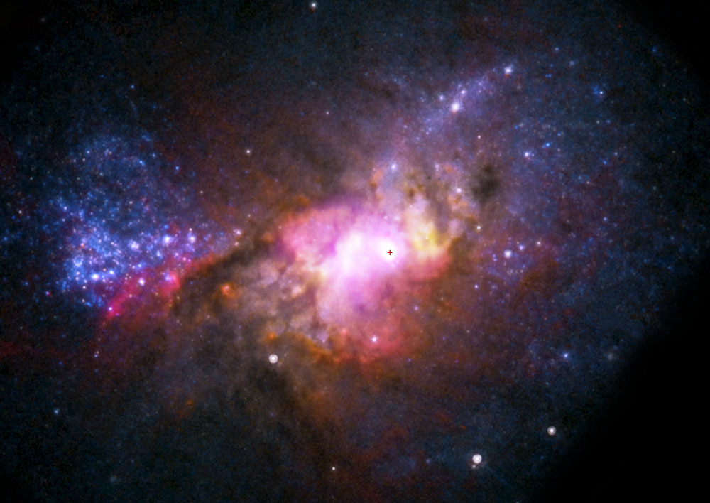 supermassive black hole in a galaxy that has dark blues, purples, reds, and yellows