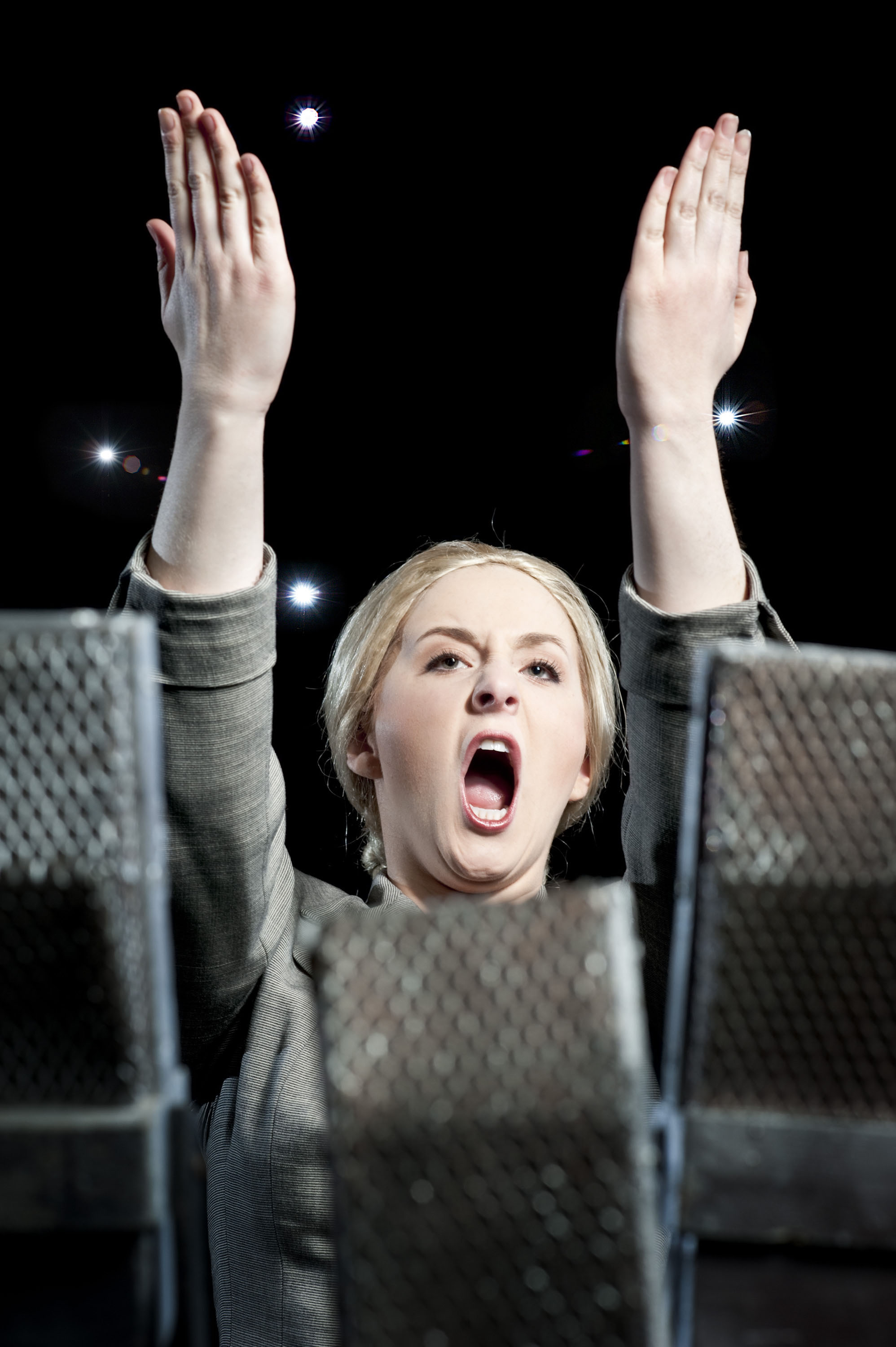 Woman singing with  both arms high in the air on stage