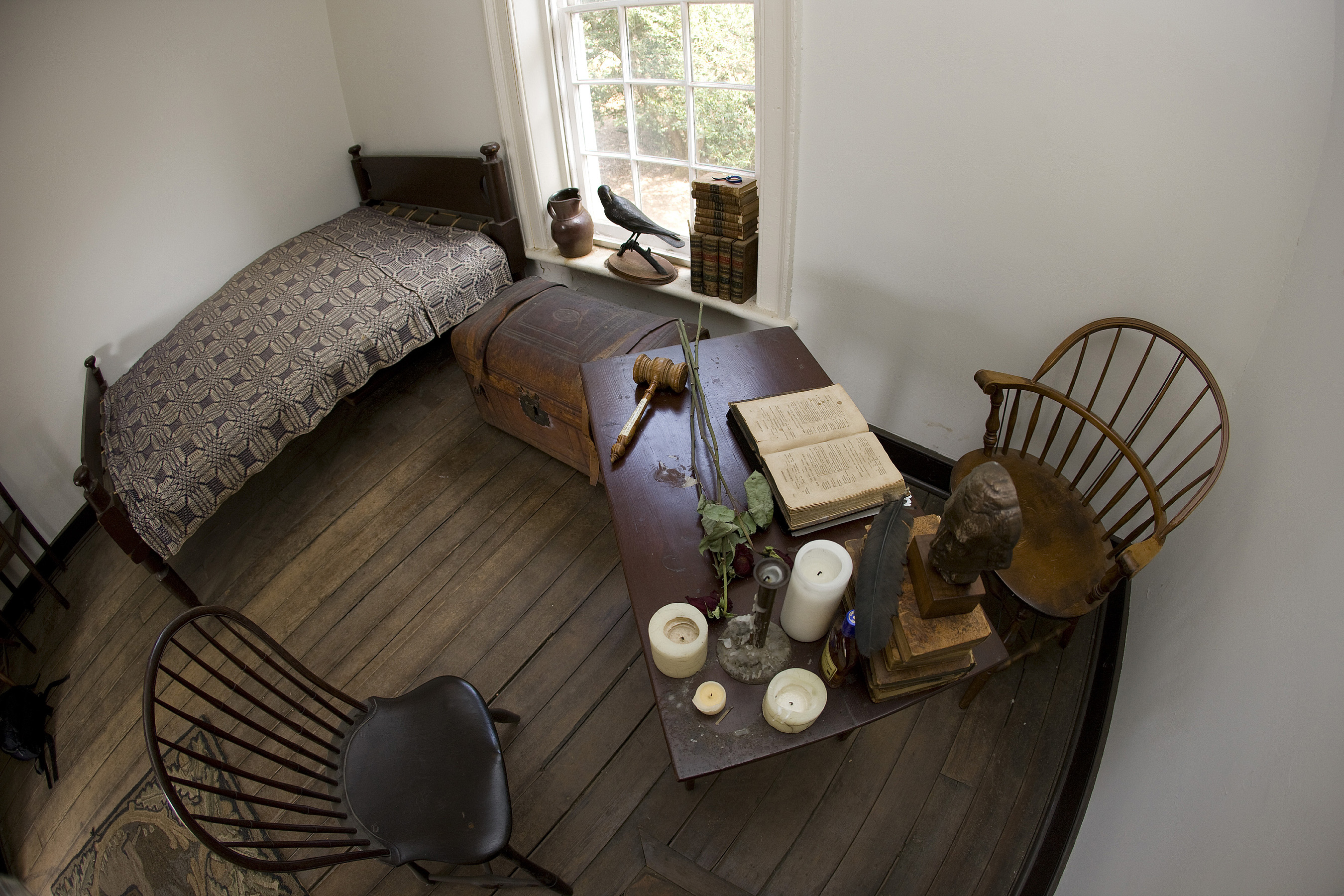 Bed, trunk, desk, chairs, candles, and old books sit in the Lawn room 13 where Edgar Allan Poe lived