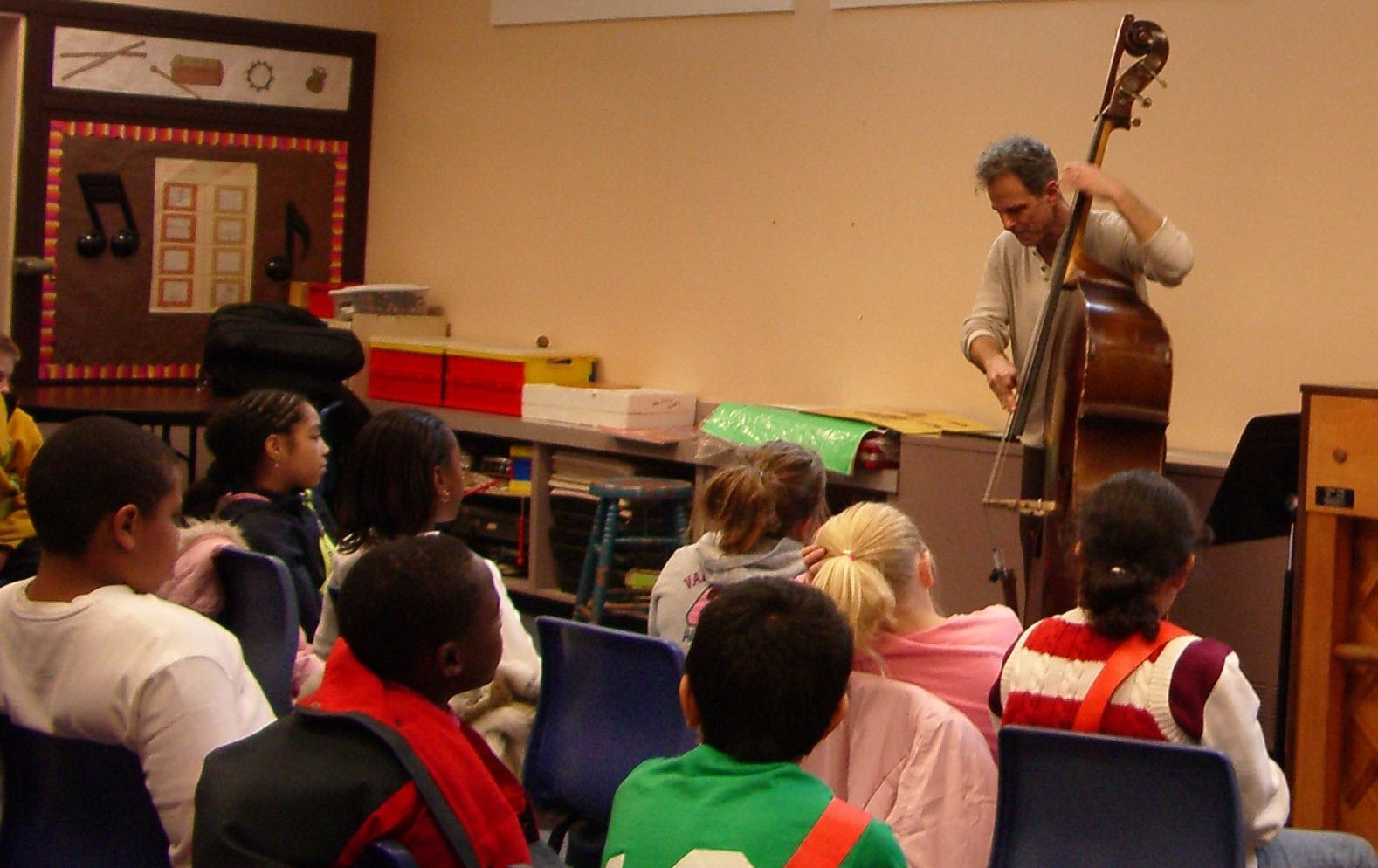 Students listen to a man play an upright bass