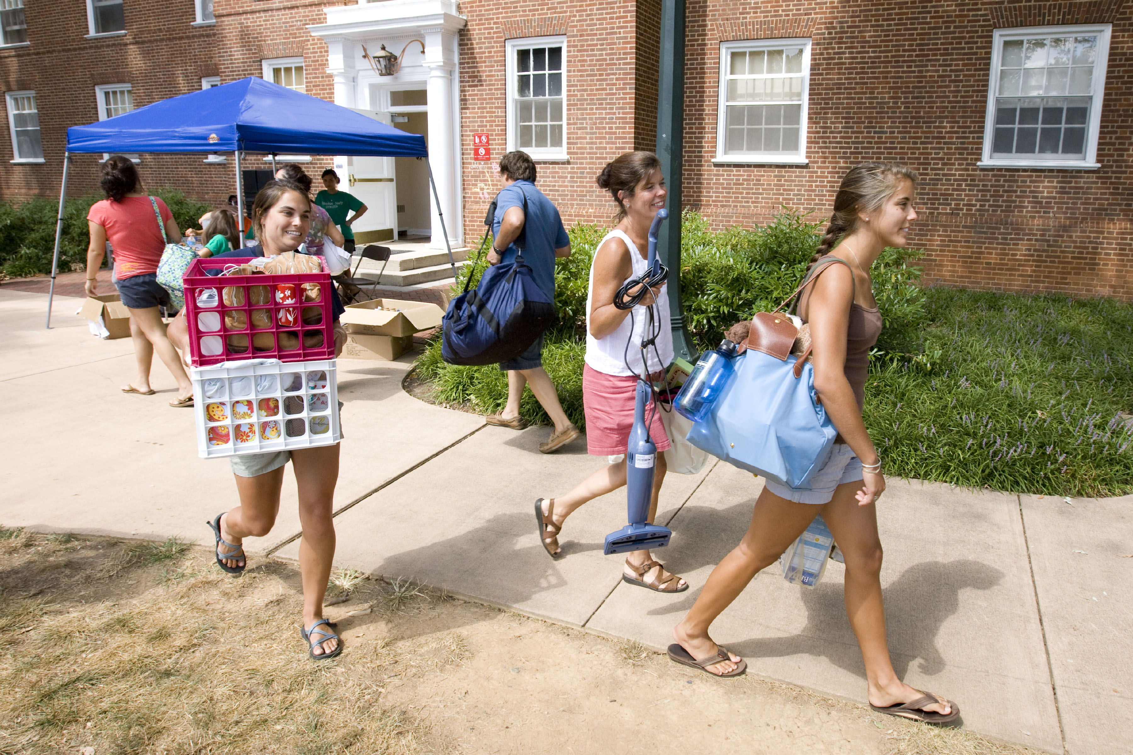 Students and their families carry personal belongings into a dorm