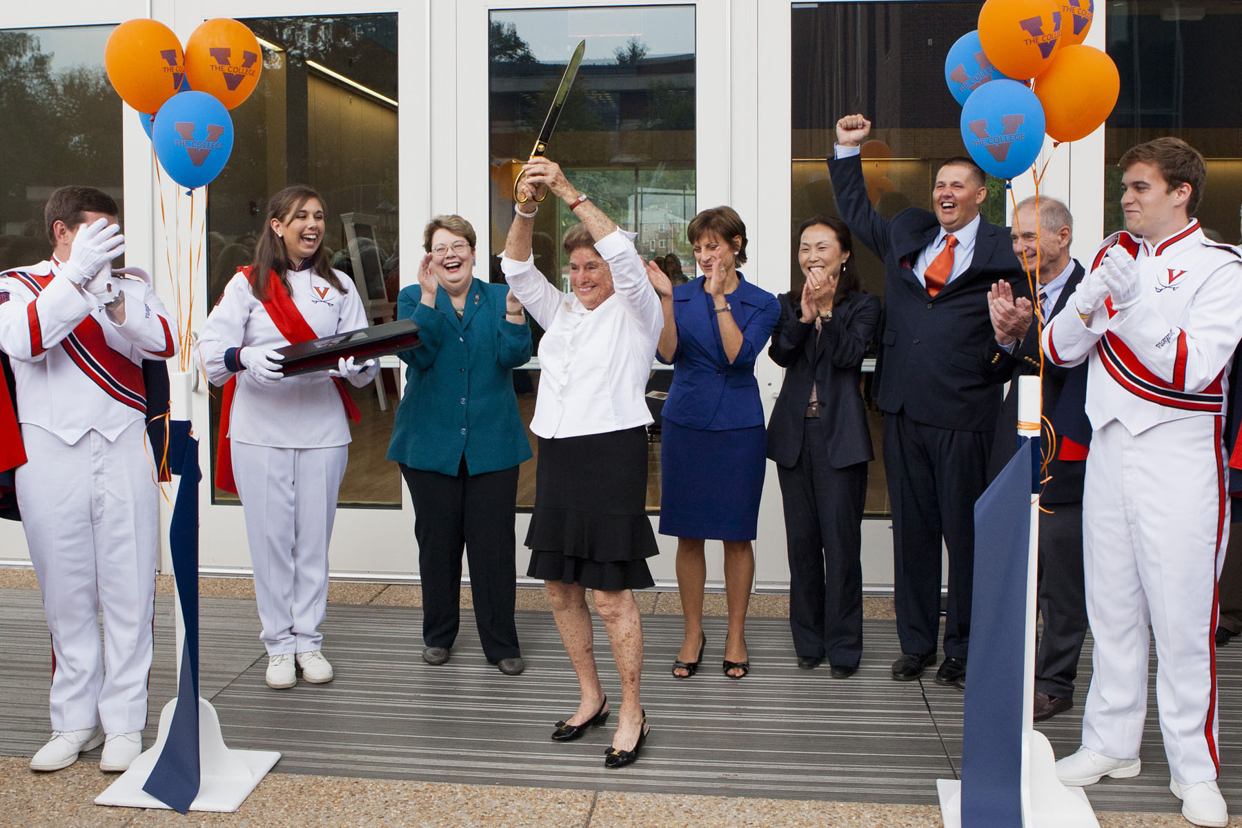 Hunter Smith cuts the ribbon on the band building with a saber as band members and UVA executive members cheer