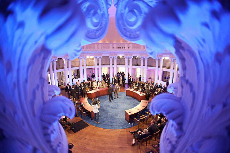 Looking through the column topper in the rotunda dome room to a crowd of people sitting and standing talking before an event