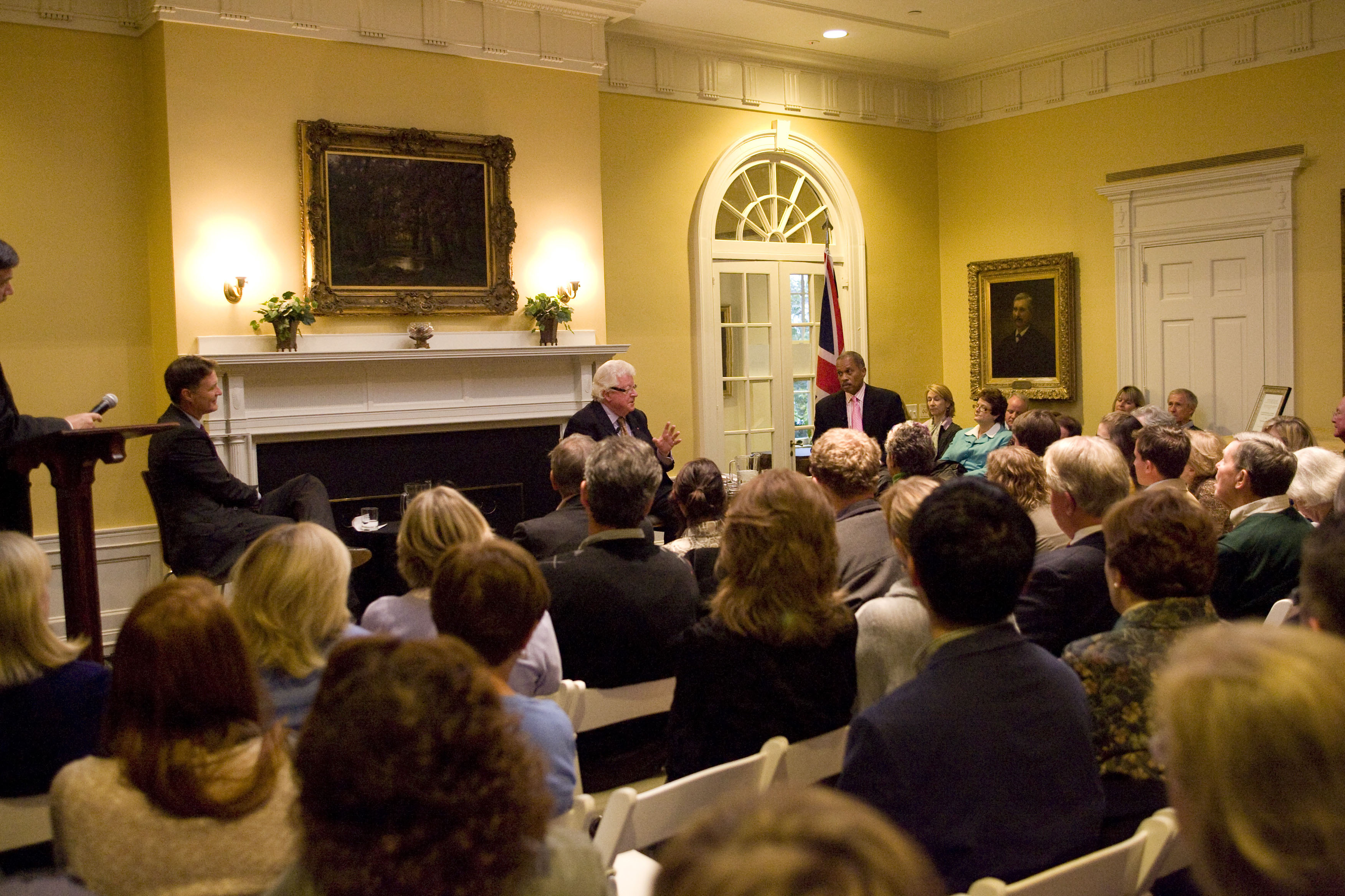 Group of people listen to a man speaking at the front of a room during a panel discussion