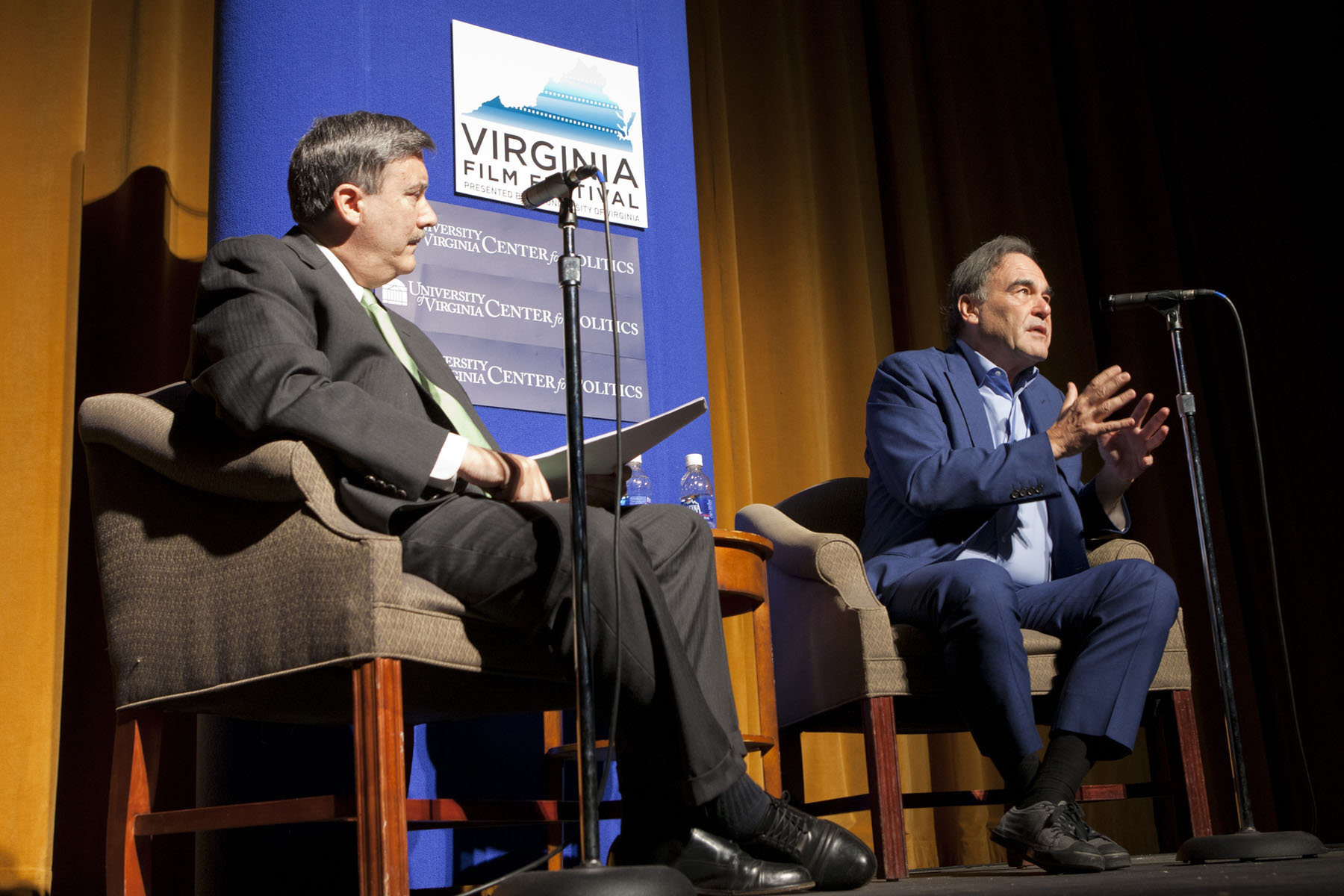Oliver Stone, right, and Larry Sabato, left, talk to a crowd of people from the stage