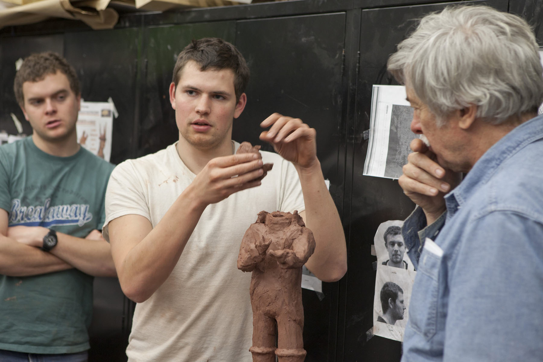 William Bennett, right, listens to a student who is holding the head of a clay figure
